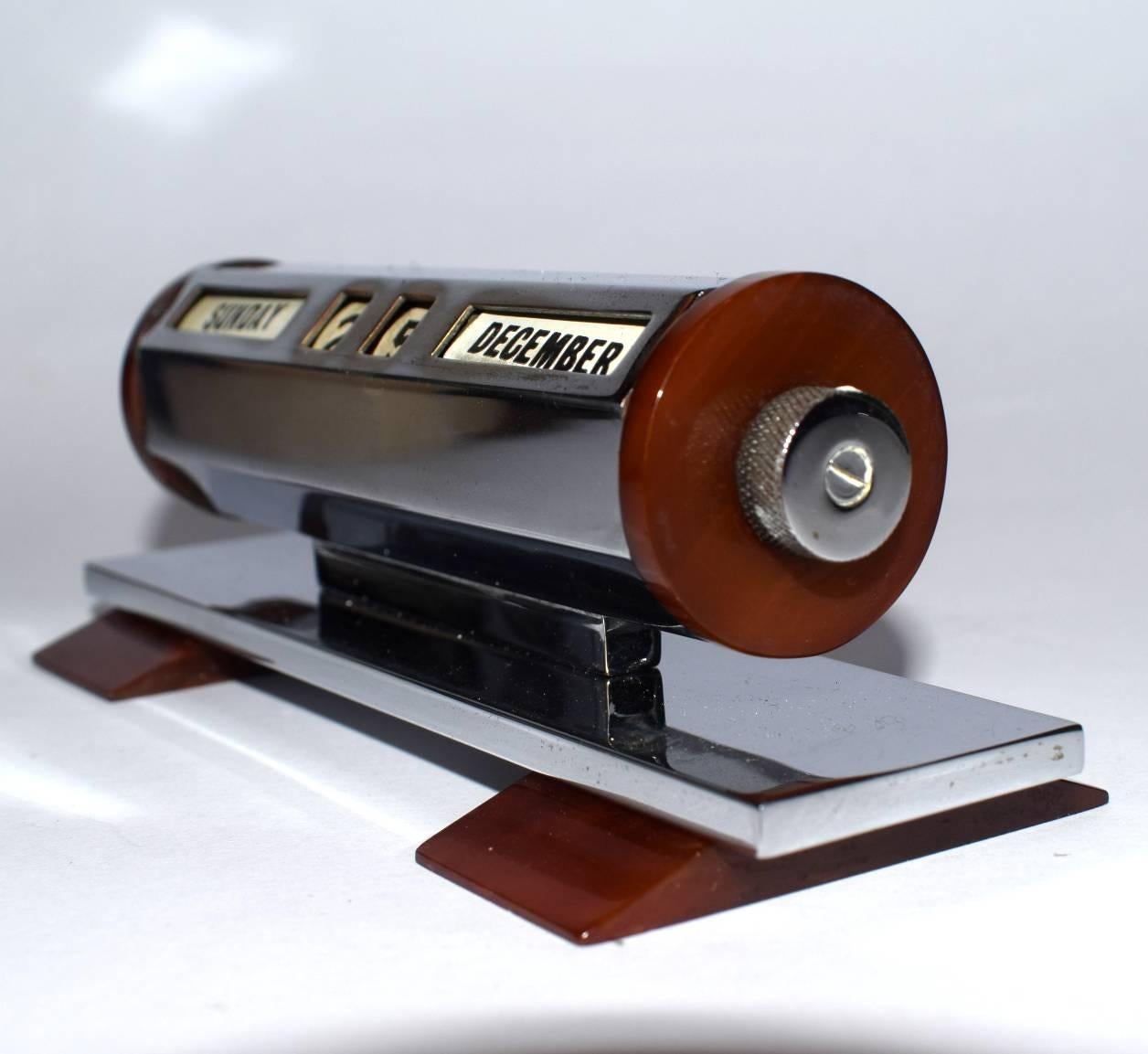 Stylish and totally authentic Art Deco desk calendar which displays the day, month etc. Quite heavy for a small item. The body is chromium plated and is in way above average condition, no tarnishing or pitting. Accented with caramel phenolic