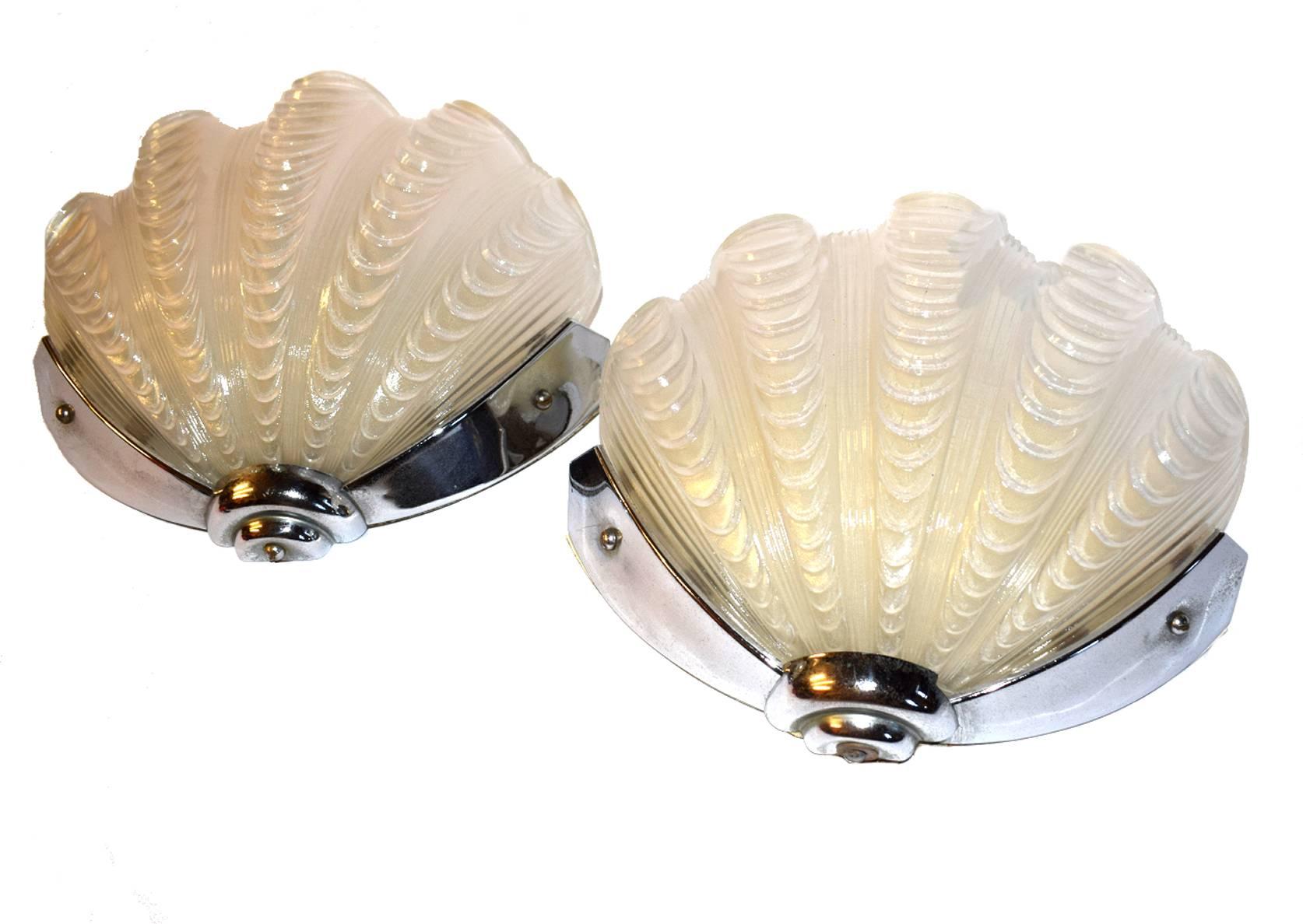 A beautiful matching of Art Deco wall lights of shell form. The chrome frames are in very good original condition which when fitted to the wall hold the beautiful white shades firmly in place. Truly beautiful and will work perfectly with the most