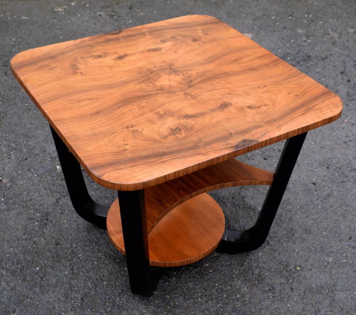 Stylish and totally authentic Art Deco English occasional table. A segmented walnut veneered top with legs that sweep down to a figured walnut under tier with ebonised accents makes this a very attractive piece. We've had the whole table fully and