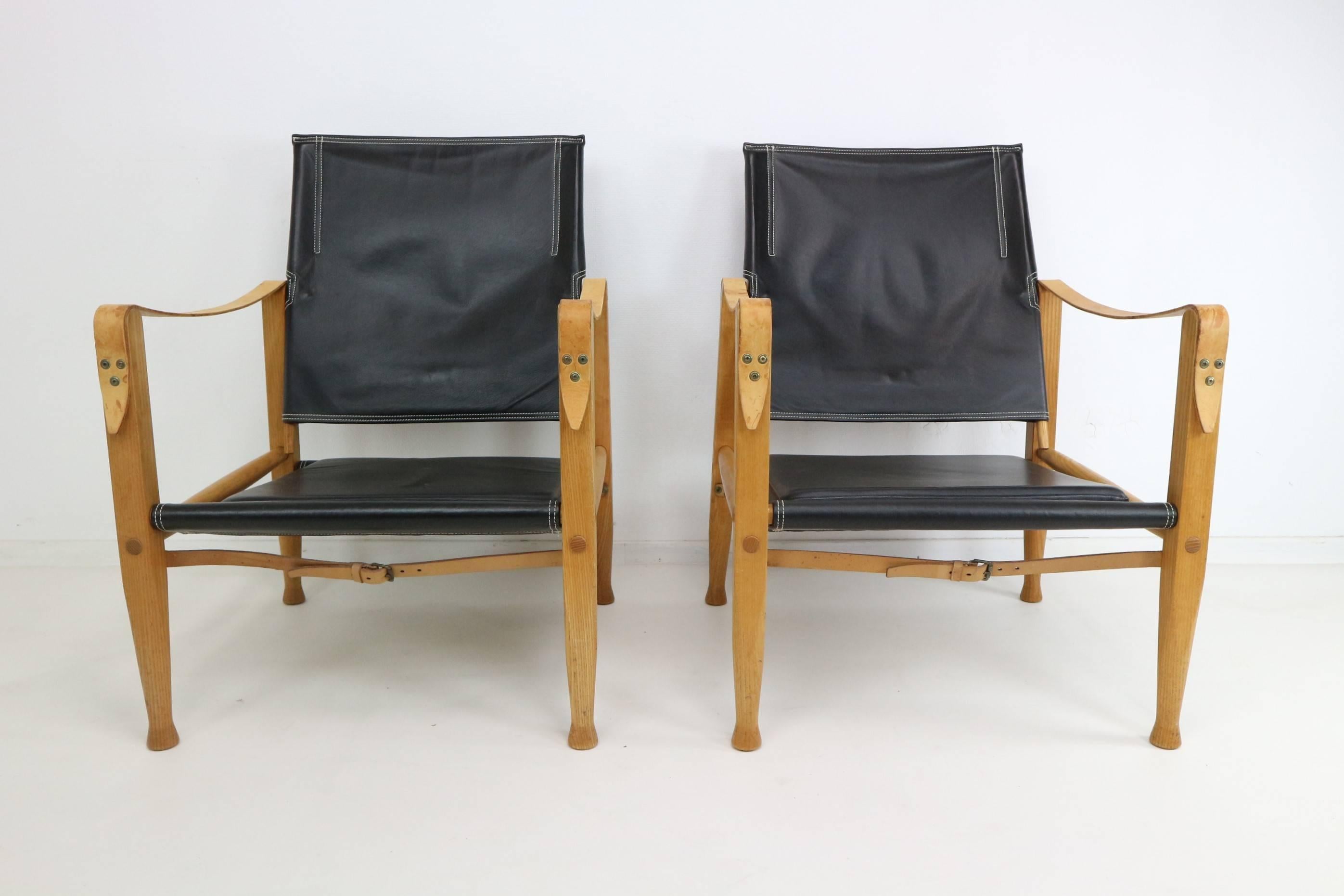 The original Danish safari chair by Kaare Klint for Rud. Rasmussen.

First produced in 1933, this pair were made in the 1950s from strikingly grained ashwood.

With black leather seat, backrest and cushion, tan leather straps and brass details.

It