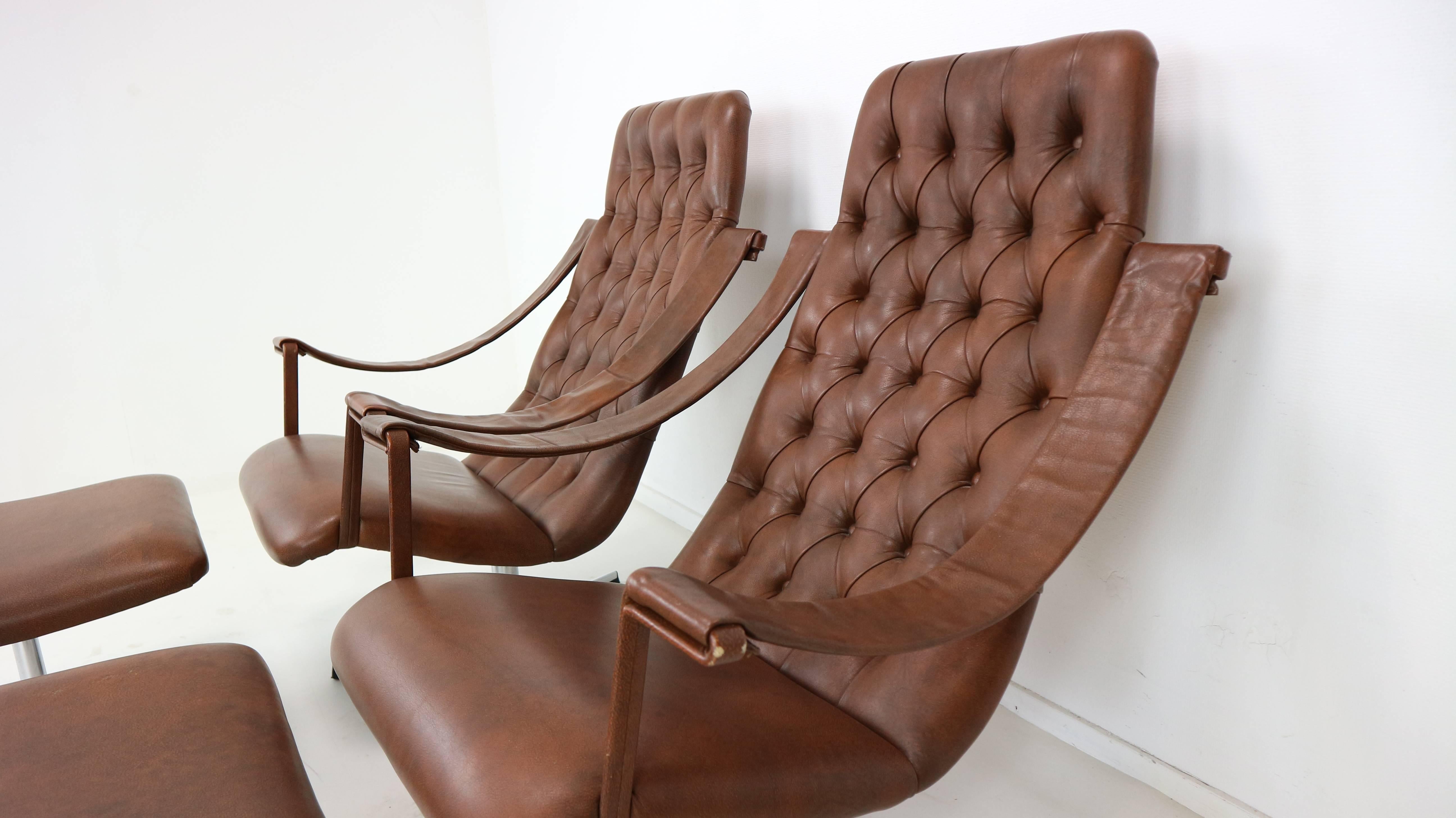 Two rare lounge swivel chairs and ottoman, rust-brown skai leather upholstery, free hanging armrests and a swivel chrome base. The lounge chair with the unusual armrests is designed by Geoffrey Harcourt for Artifort Netherlands, 1960s.