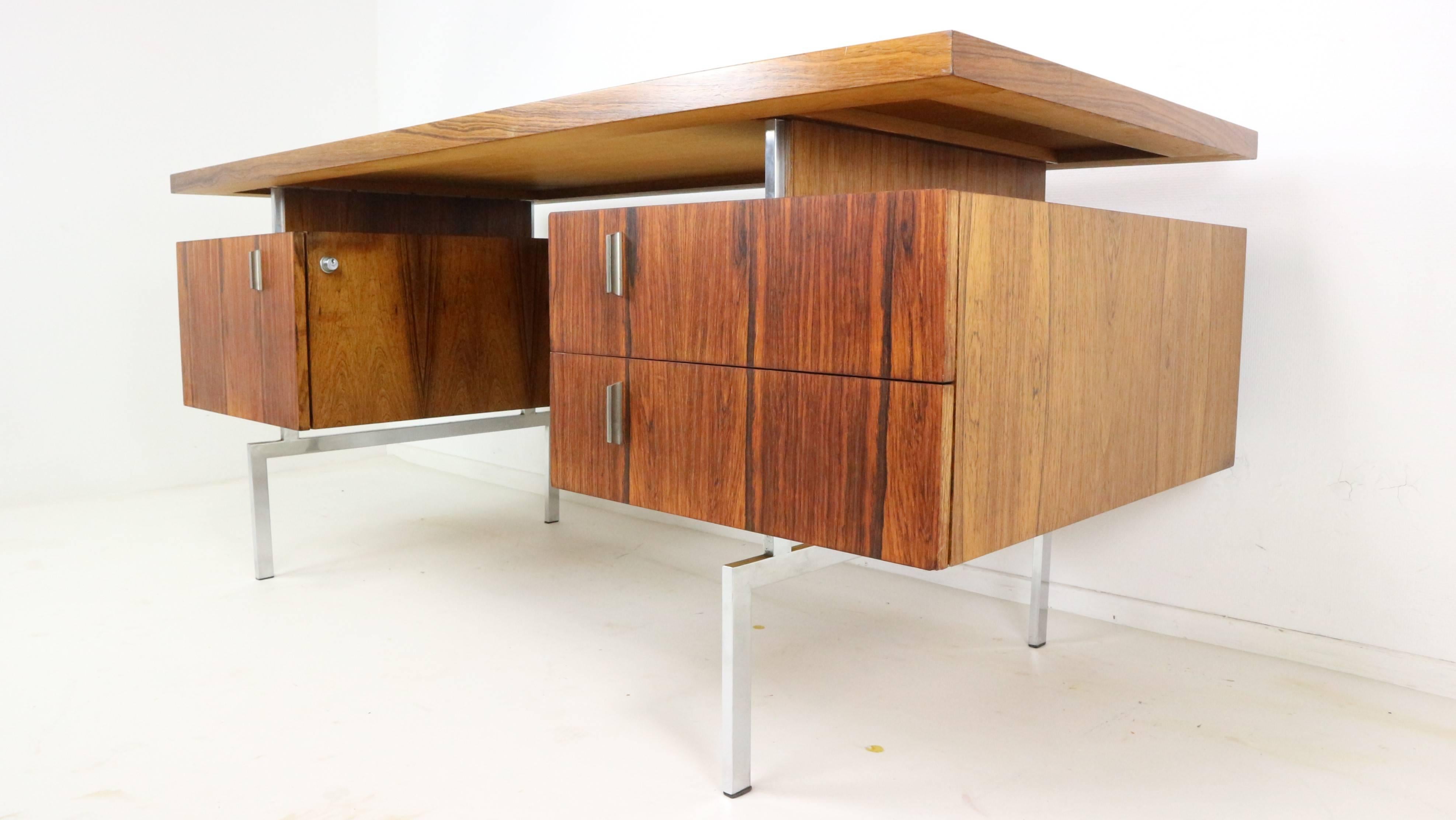 Beautiful writing desk from the 1960s, made from rosewood and chrome frame and details. Including bookcase in the backside. The desk comes with the original keys. It shows some ware of use but the top is refurbished and looks brand new. One feed is