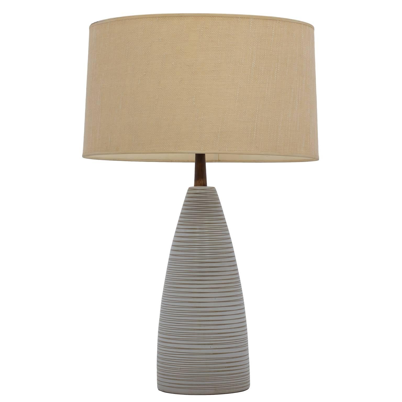 Mid-century table lamp from the pottery studio of Jane and Gordon Martz. This table lamp is in the Martz's signature neutral toned, eggshell, off-white ceramic glaze with a walnut neck. It features an incised linear design going through the glaze