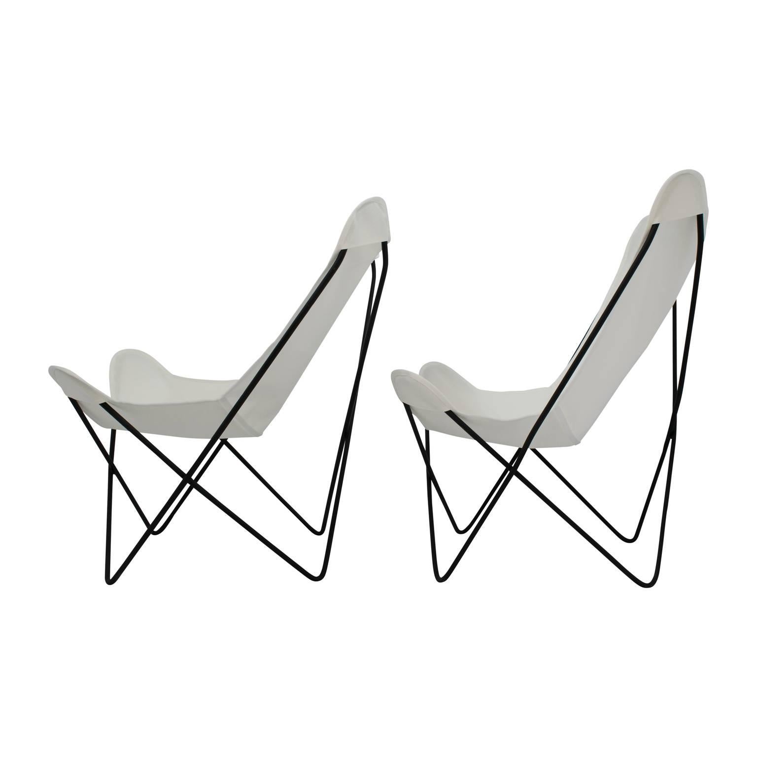 Two vintage butterfly chairs with new white slings, in the style of Jorge Ferrari Hardoy for Knoll. The butterfly chairs have welded iron frames with a matte black finish. These Mid-Century chairs can be used indoors or outdoors, and they can be