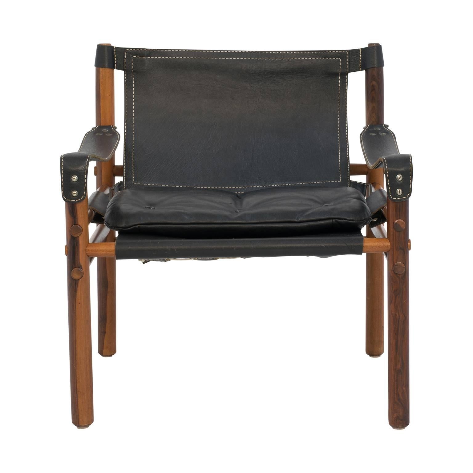 Fabulous Sirocco safari chair by the Swedish designer Arne Norell Sirocco in rosewood and original black leather. The chair has a beautiful rustic modern vibe: rugged black leather with white over-stiching on a rosewood frame. Norell’s Sirocco chair