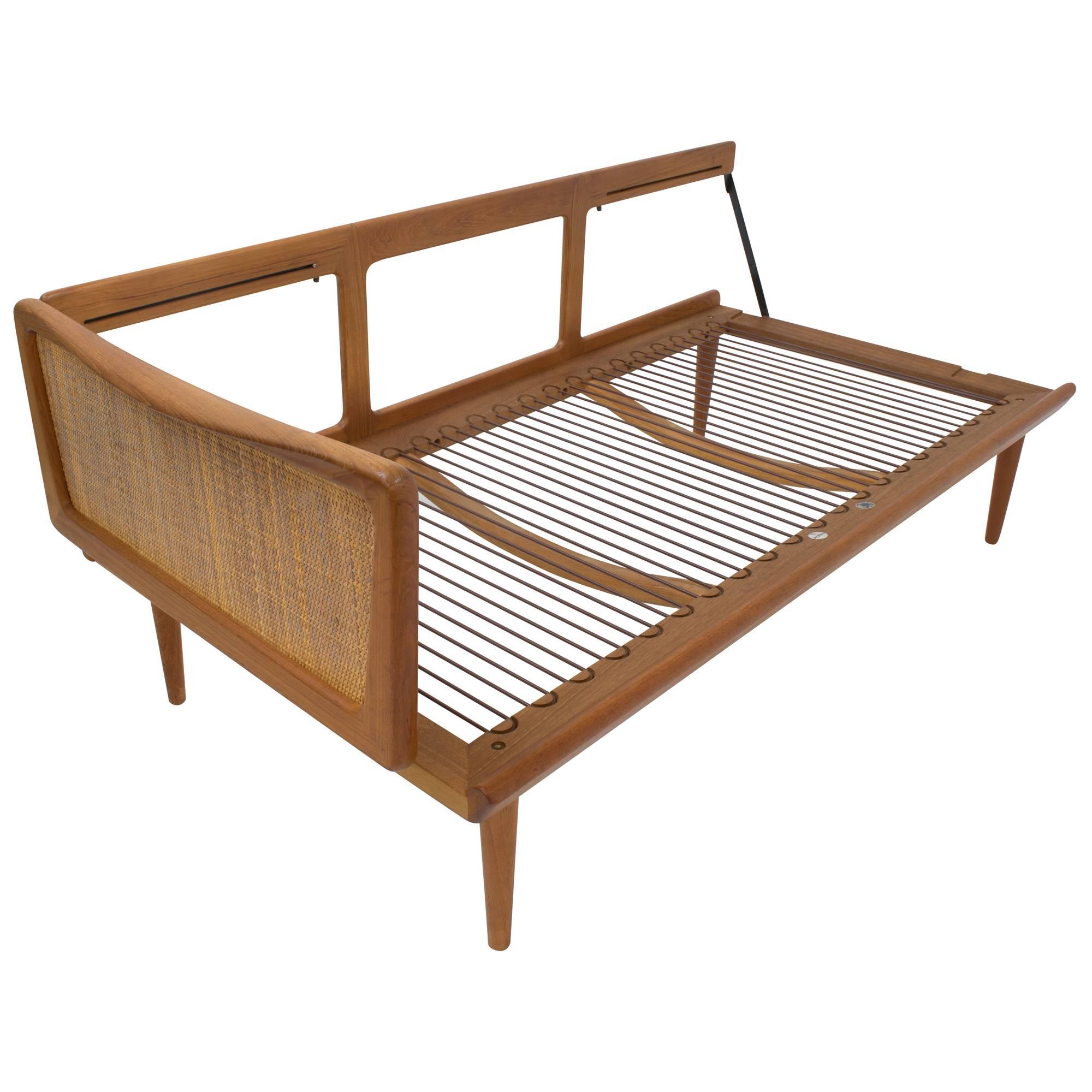 This beautiful and rare daybed was designed by Peter Hvidt and Orla Mølgaard-Nielsen and crafted by France and Son for John Stuart. This model FD451 seating has a caned, fold-down arm that allows the piece to convert from a compact sofa to a daybed.