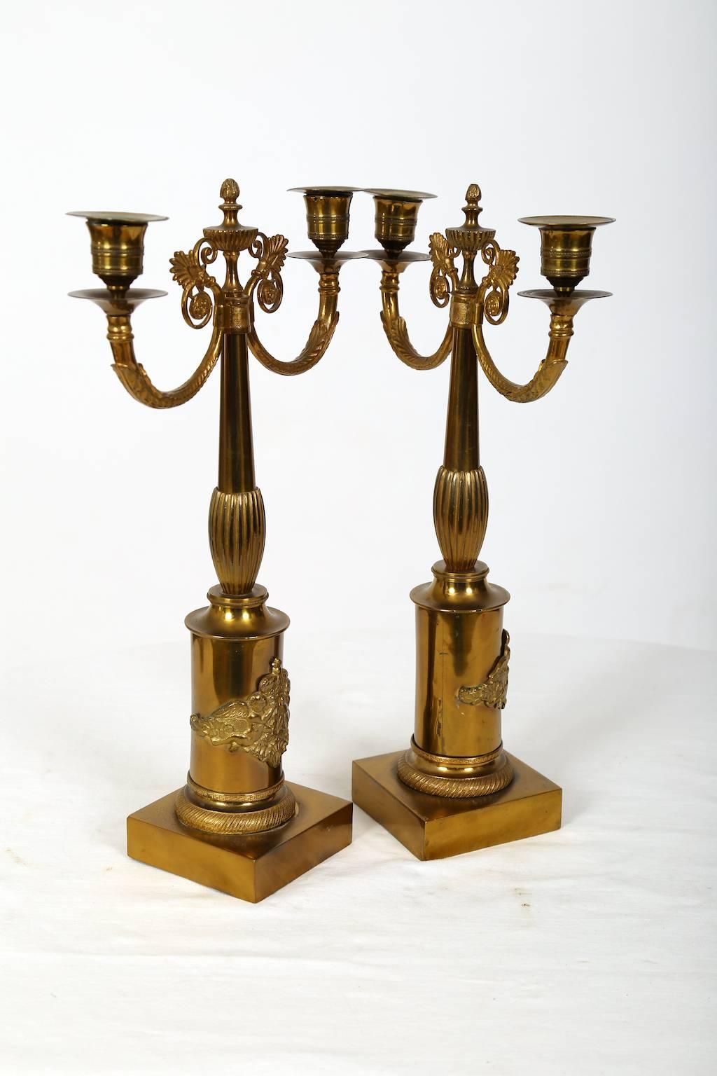 This elegant pair of gilded brass candelabras are most likely from Sweden.
The are very typical late Empire, beautiful and with a decorative shield on the front consisting of two angels holding a royal crown above an oak leaf.
