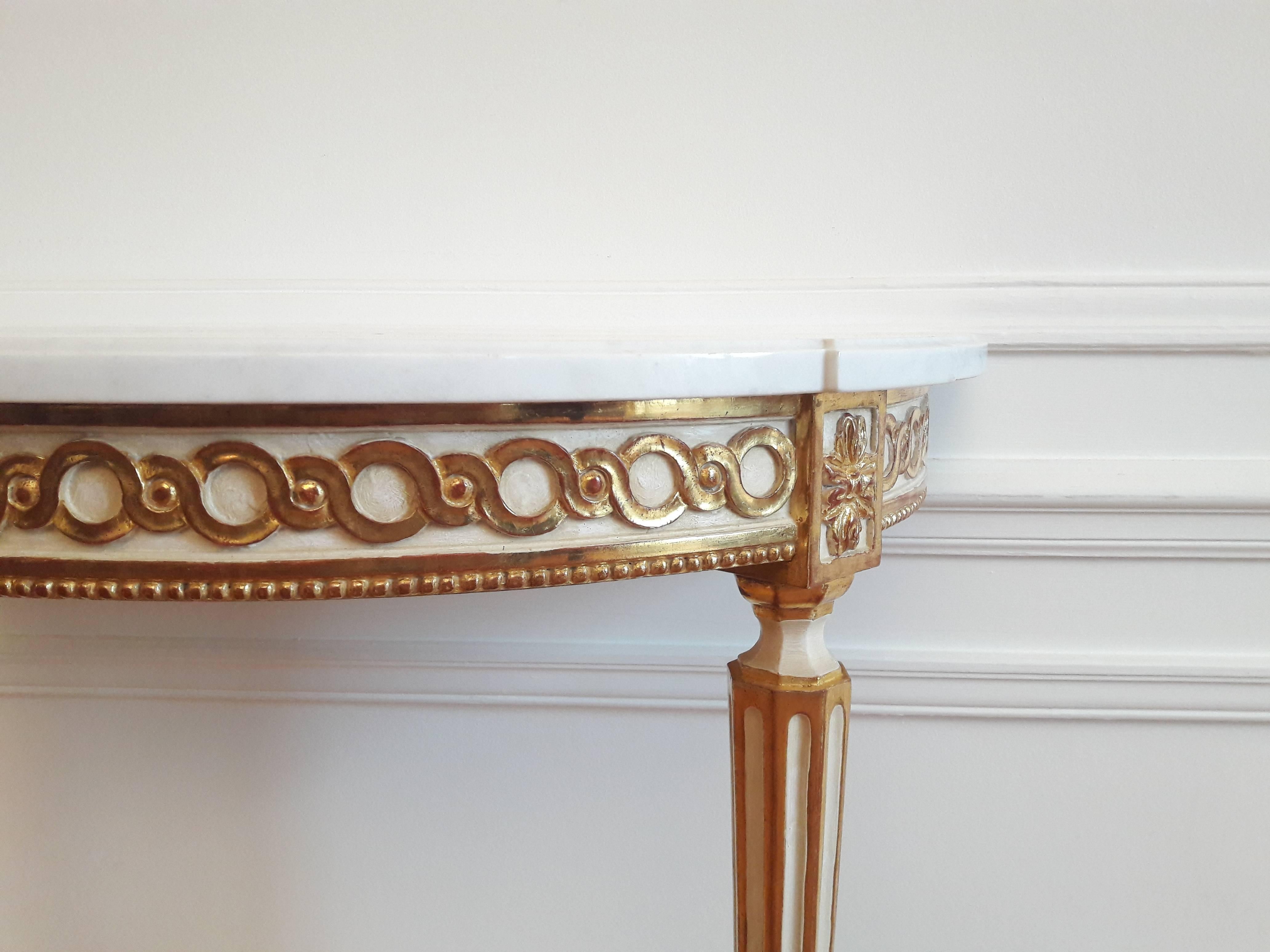 Console antique de style Louis XVI and golden leaf, topped with a white demilune marble Carrara.
The feet are fluted and carved, decorated with gold leaf on all sides.
The console rests on two feet and is to fix on the wall.