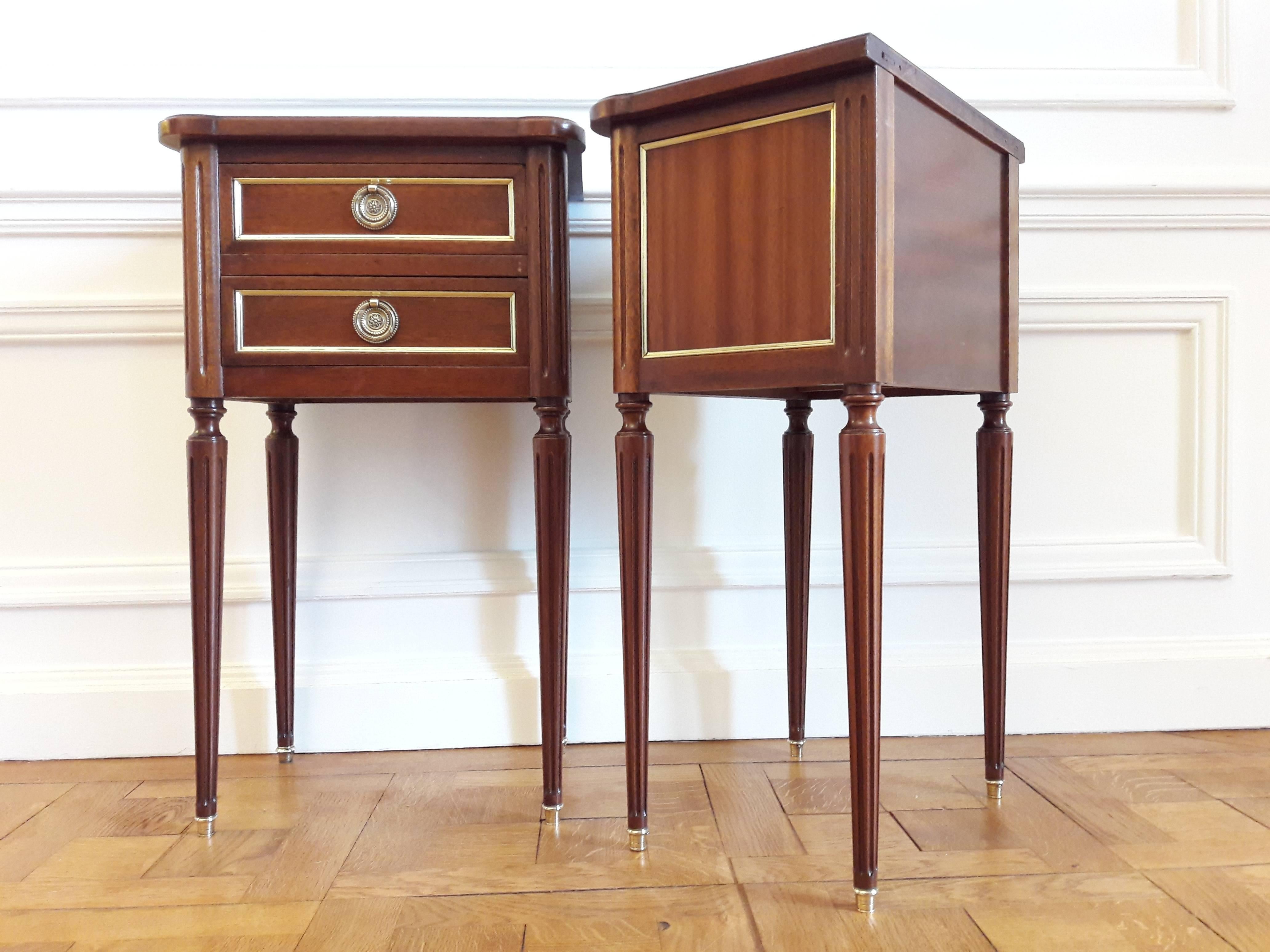 Antique French Louis XVI style pair of nightstands in varnished wood, fluted legs finished with golden bronze clogs. 
Two dovetailed small drawers with brass details.