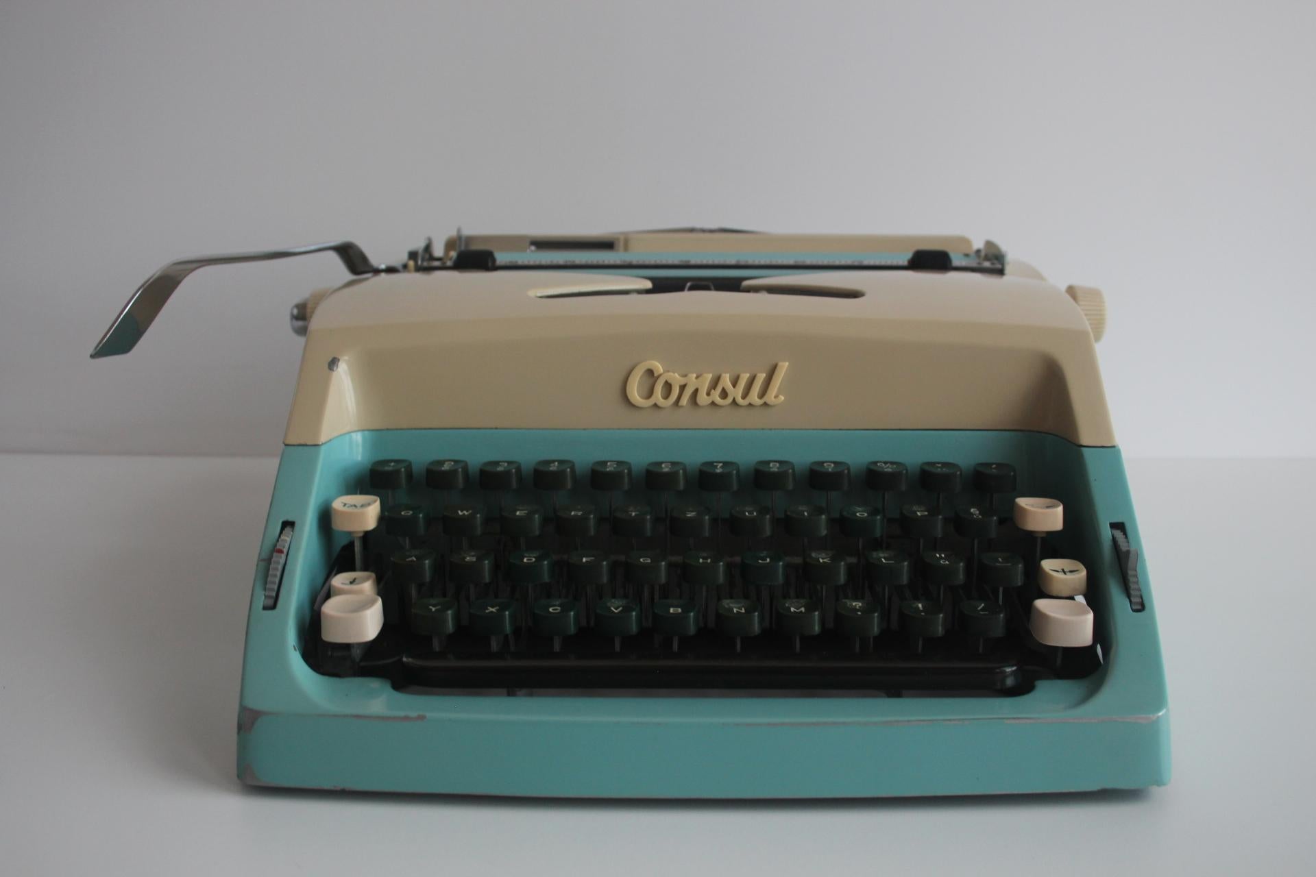 Questa accattivante macchina da scrivere di metà secolo di Consul è stata prodotta in Cecoslovacchia negli anni Sessanta. Presenta una combinazione di colori bicolore in crema e blu acqua, con tasti arrotondati in verde scuro e accenti bianchi.

La