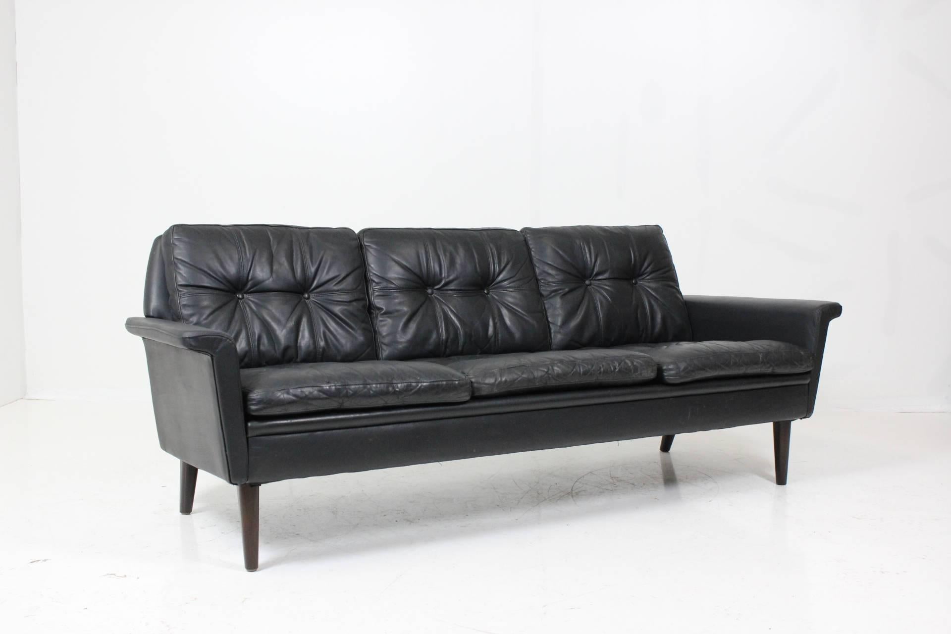 Classic Mid-Century design three-seat cushion sofa in black patinated leather by Hans Olsen's. Partly restored, new armrests leather upholstery, minor signs of wear, overall good condition.