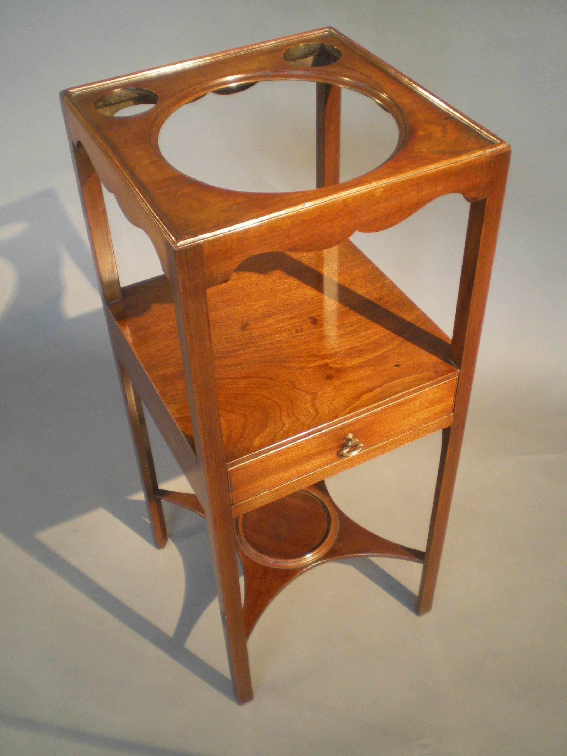 A good George III period mahogany washstand, the top with circular cut-outs for a bowl and soap dishes, above a plain shelf with drawer and supported on square uprights.