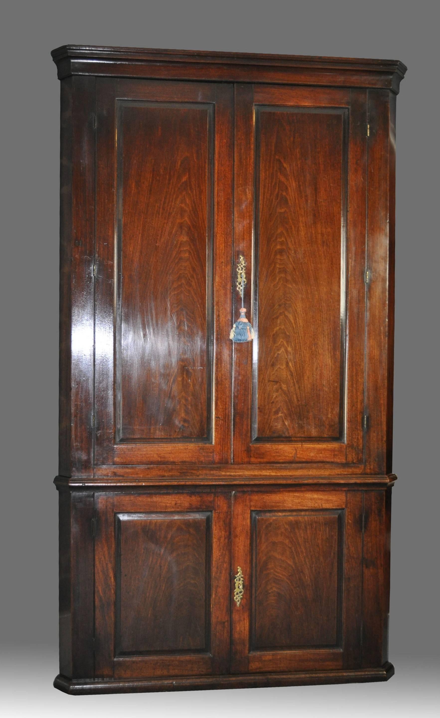 A fine quality mid-18th century mahogany four-door, full height, standing corner cupboard with plain cavetto cornice above a pair of fielded panelled doors enclosing shaped shelves and an internal, flap- covered compartment, above a waist moulding