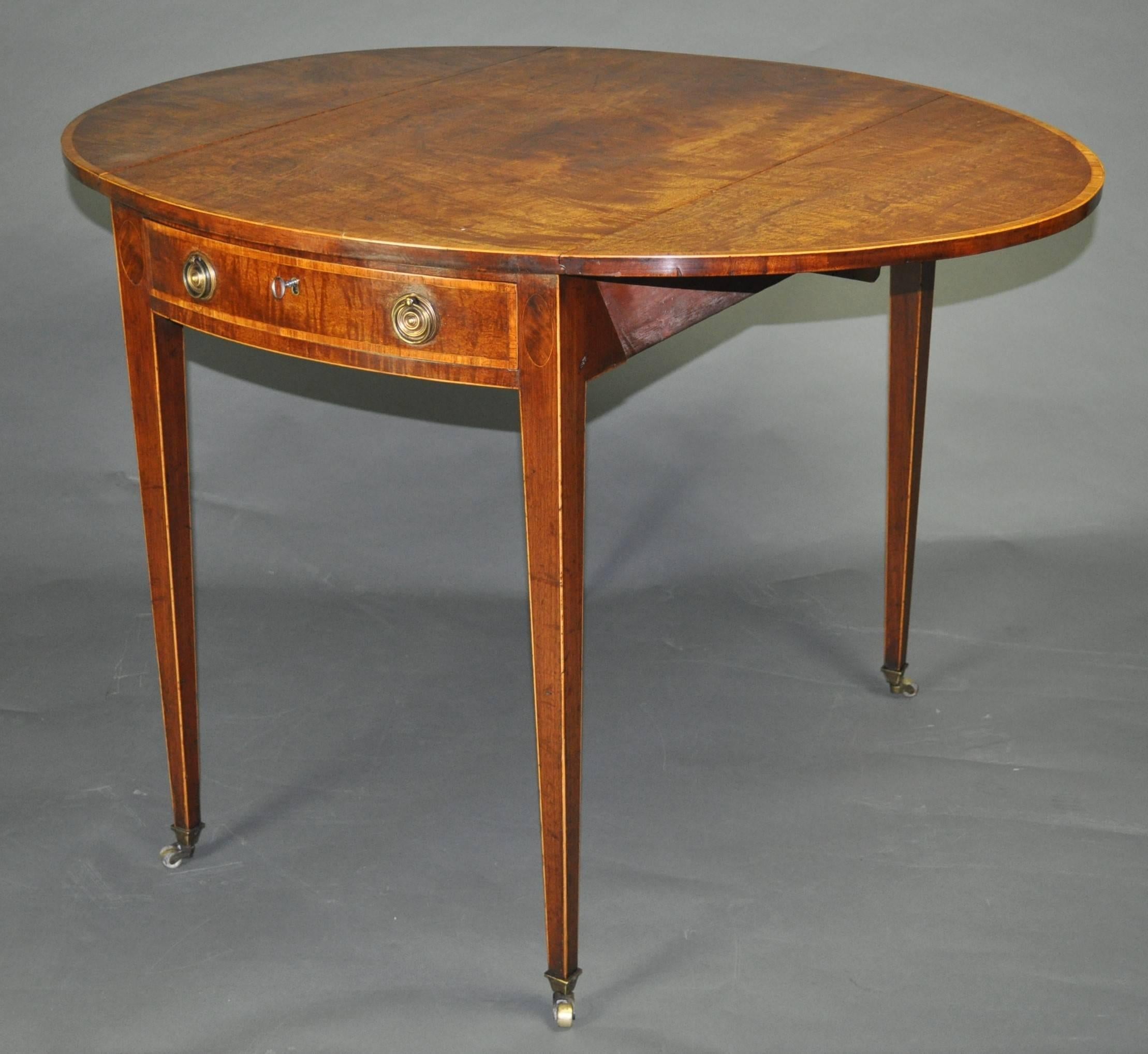 A good quality late 18th century figured mahogany oval Pembroke table, the top with lively figuring and good color, crossbanded in tulipwood, above a plain apron with similarly banded drawer and dummy drawer, standing on elegant square tapering legs