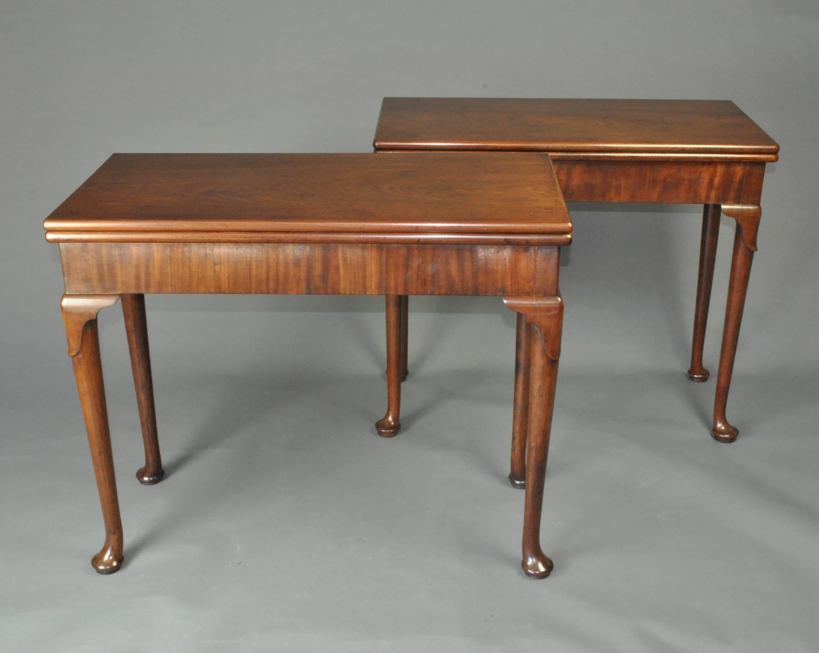 A matched pair of George II mid-18th century mahogany card tables with rectangular tops supported on concertina action bases with plain friezes and standing on lappet carved legs with pad feet. Both baize lined for cards, one 34” wide, the other 35”