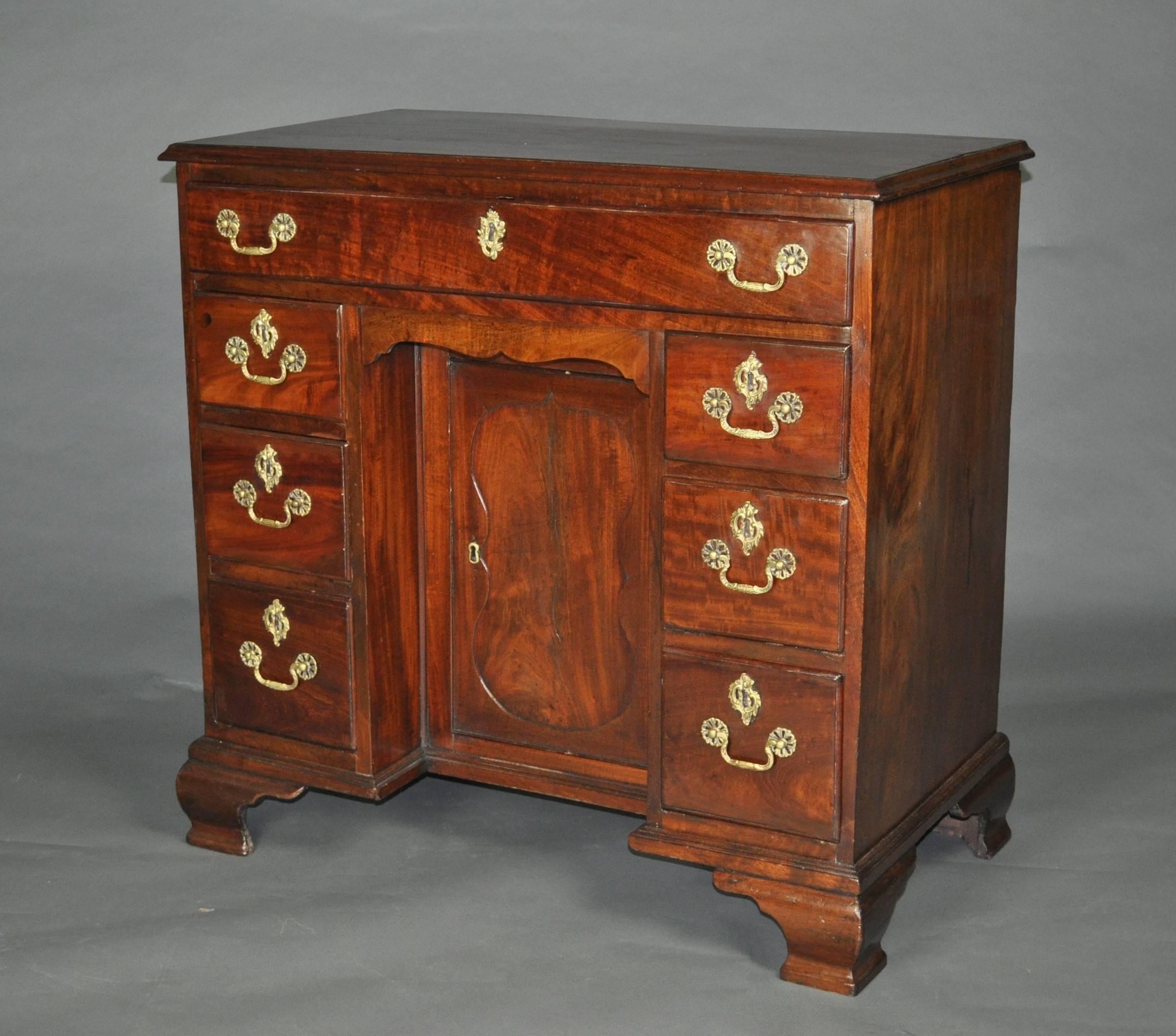 A good George III period mahogany kneehole desk or dressing table, the top with moulded edge above one long drawers and three small drawers on each side of a recessed central cupboard and hidden apron drawer. Raised on ogee bracket feet. The central