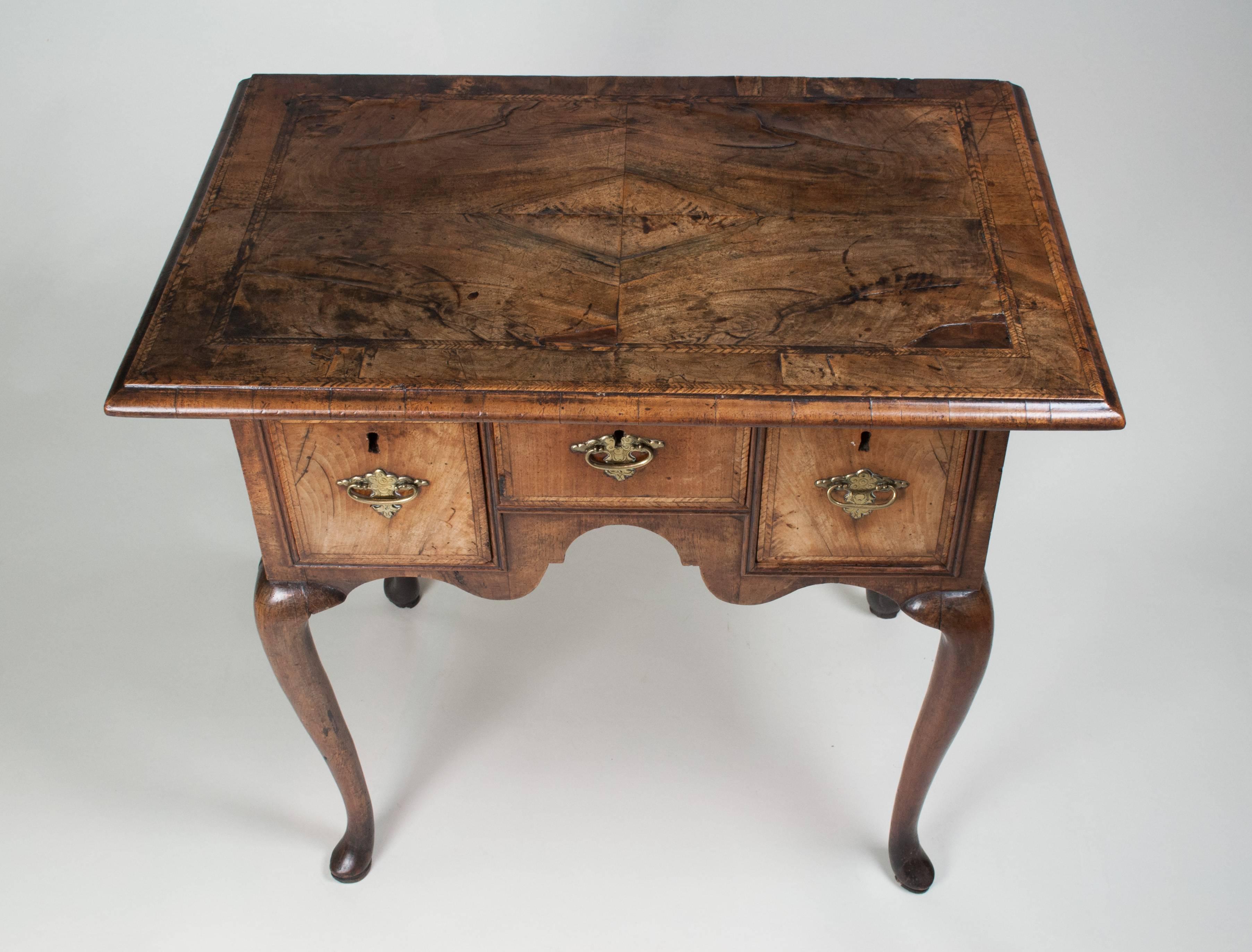 A Fine early 18th century walnut veneered three-drawer Lowboy of small size. The quarter veneered top with herringbone banding either side of a wide walnut cross-band, above three small drawers with conforming herringbone banding and set in an