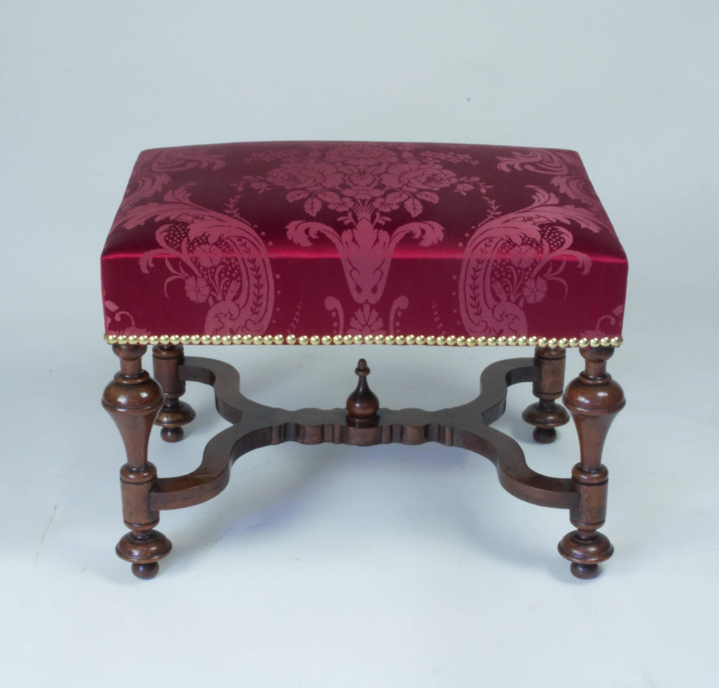 An fine and rare William and Mary period walnut stool with upholstered seat raised on turned 'cup and cover legs joined by shaped crossed stretchers with a central finial. Good color and patina.