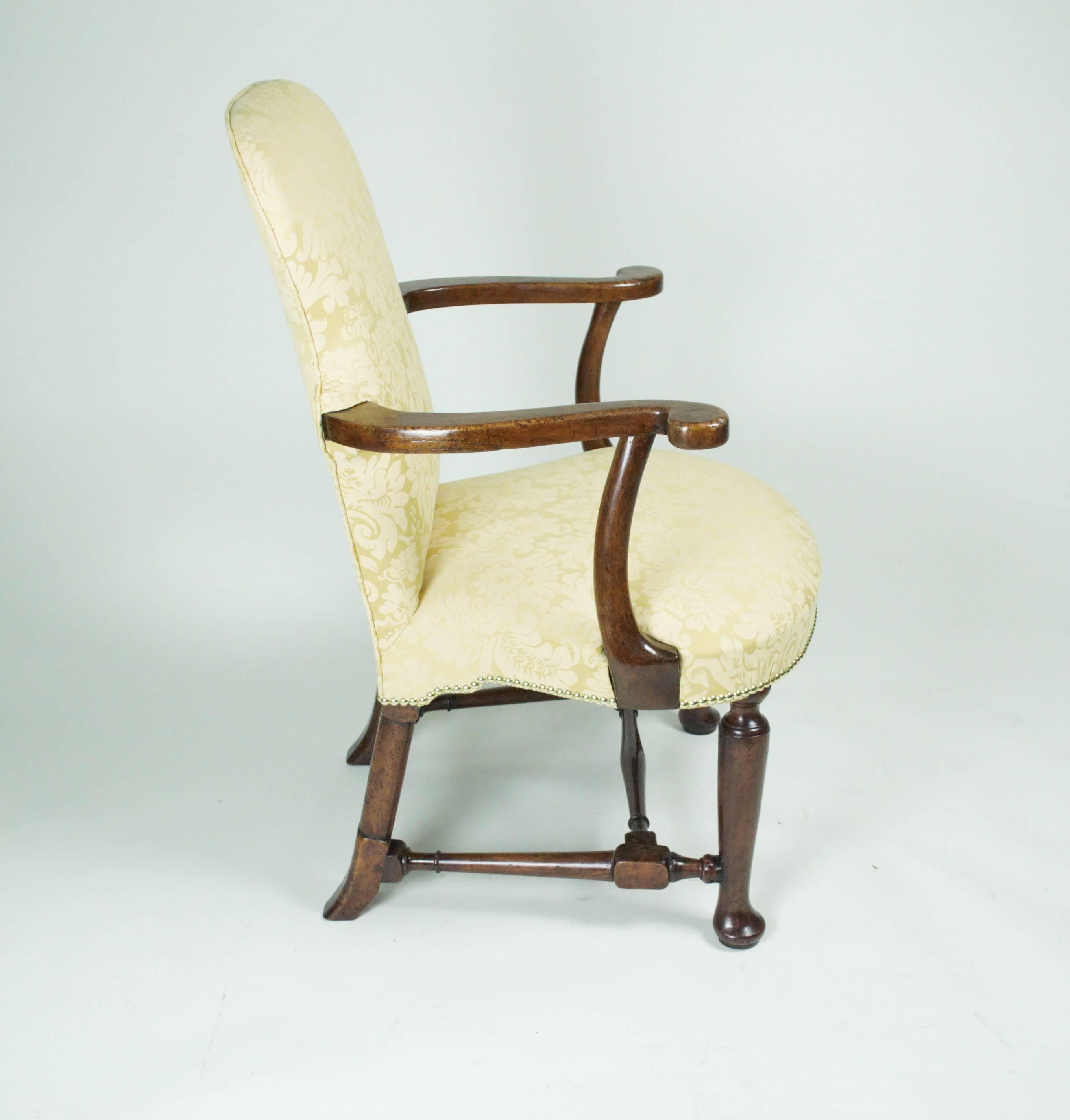 A fine George II walnut upholstered armchair, the shaped upholstered back set with scrolled arms supported on out-swept uprights, above a shell-shaped seat and raised on turned legs with pad feet to the front and section-turned back legs and