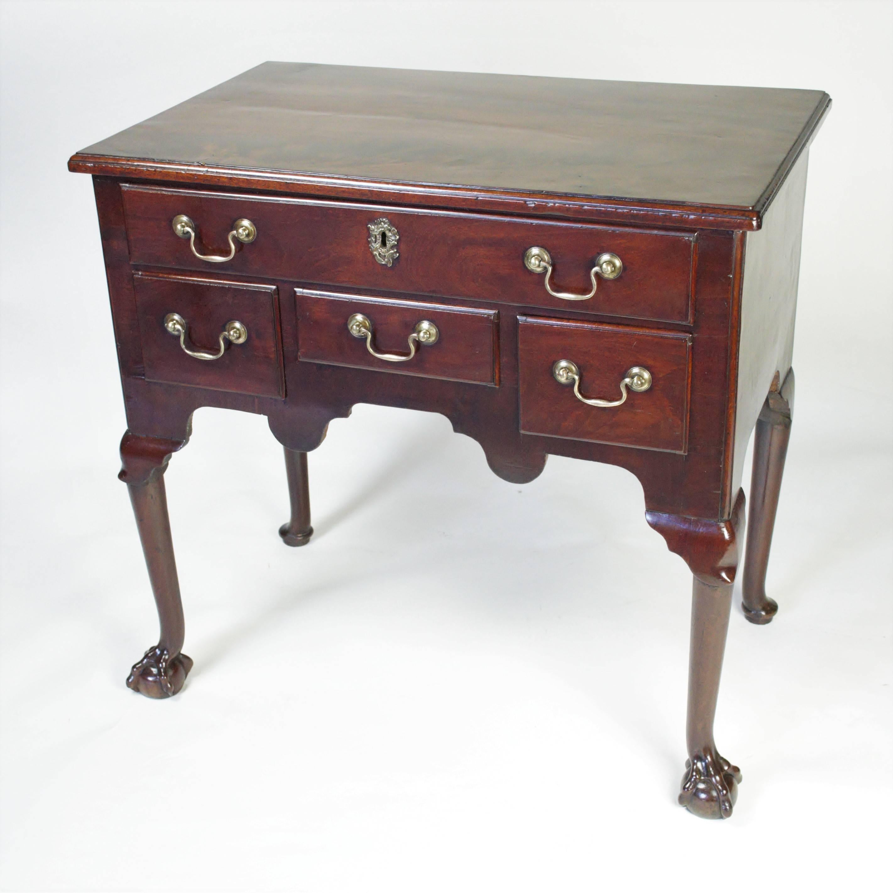 An exceptional mid-18th century mahogany lowboy with a moulded edge top above an apron fitted with one long drawer and three short drawers and raised on cabriole legs carved with lappet knees and exaggerated ball and claw feet.
Richly figured Cuban
