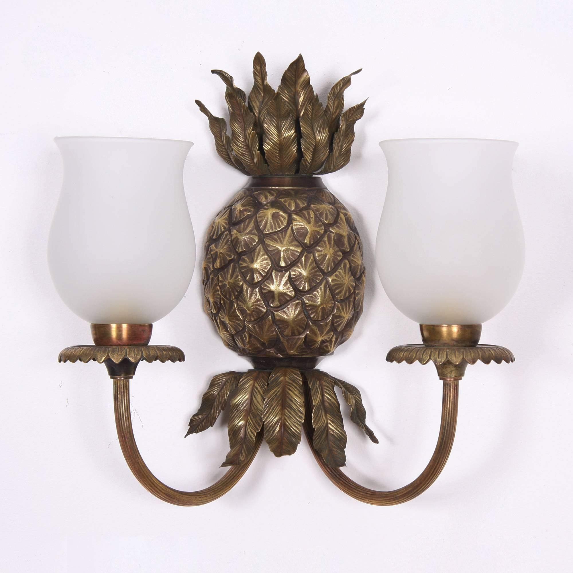 A stunning pair of pineapple wall lights by Maison Charles. Detailed pineapple shape and leaves in brass, with two light fittings each, detailed drip pans with a scalloped edging. Original frosted glass shades. Stamped with maker's mark on the