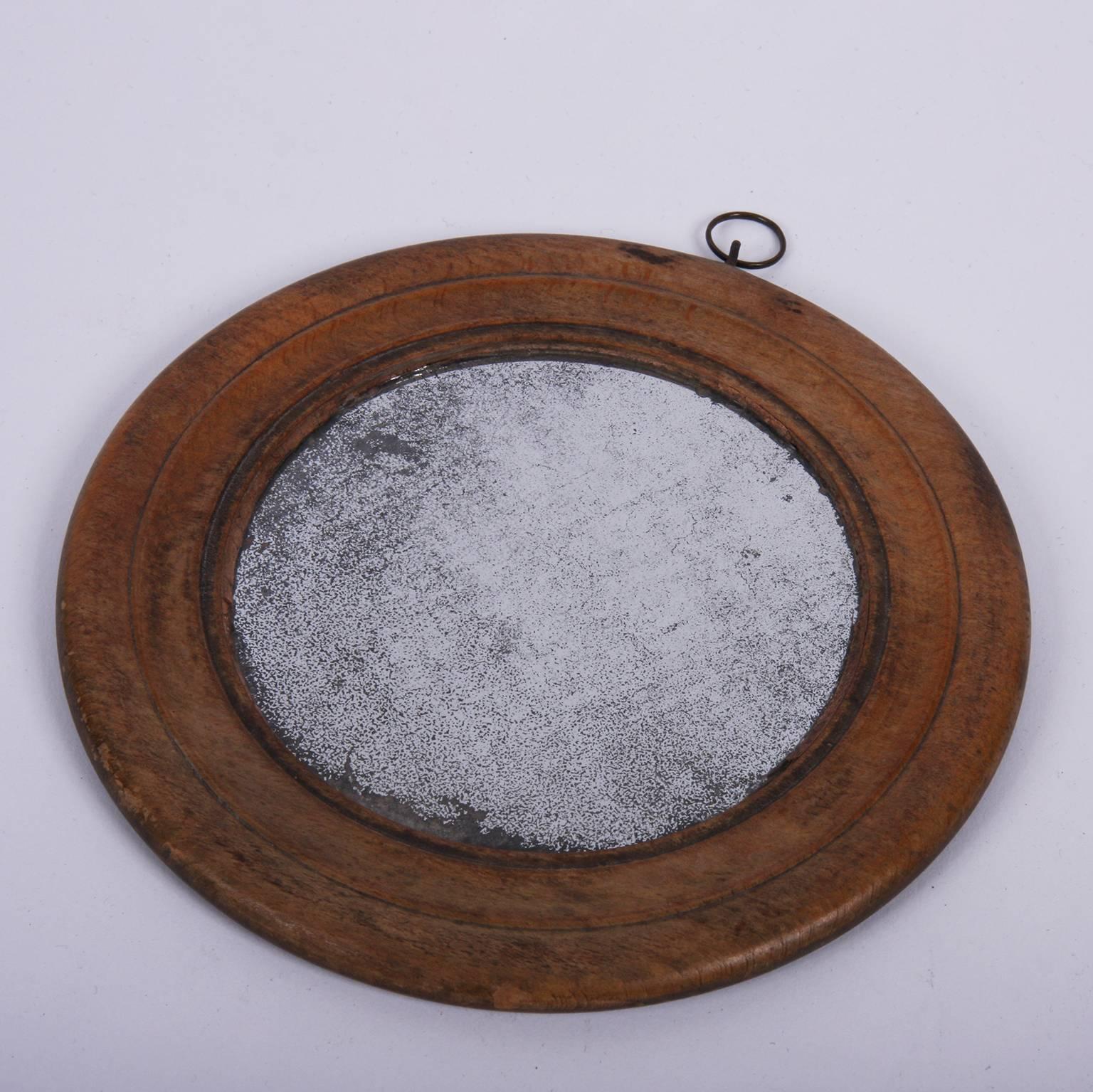 English, 19th century

A lovely small round mirror with a wooden frame and original sparkly foxed glass. This mirror has a small round metal hook on the top.