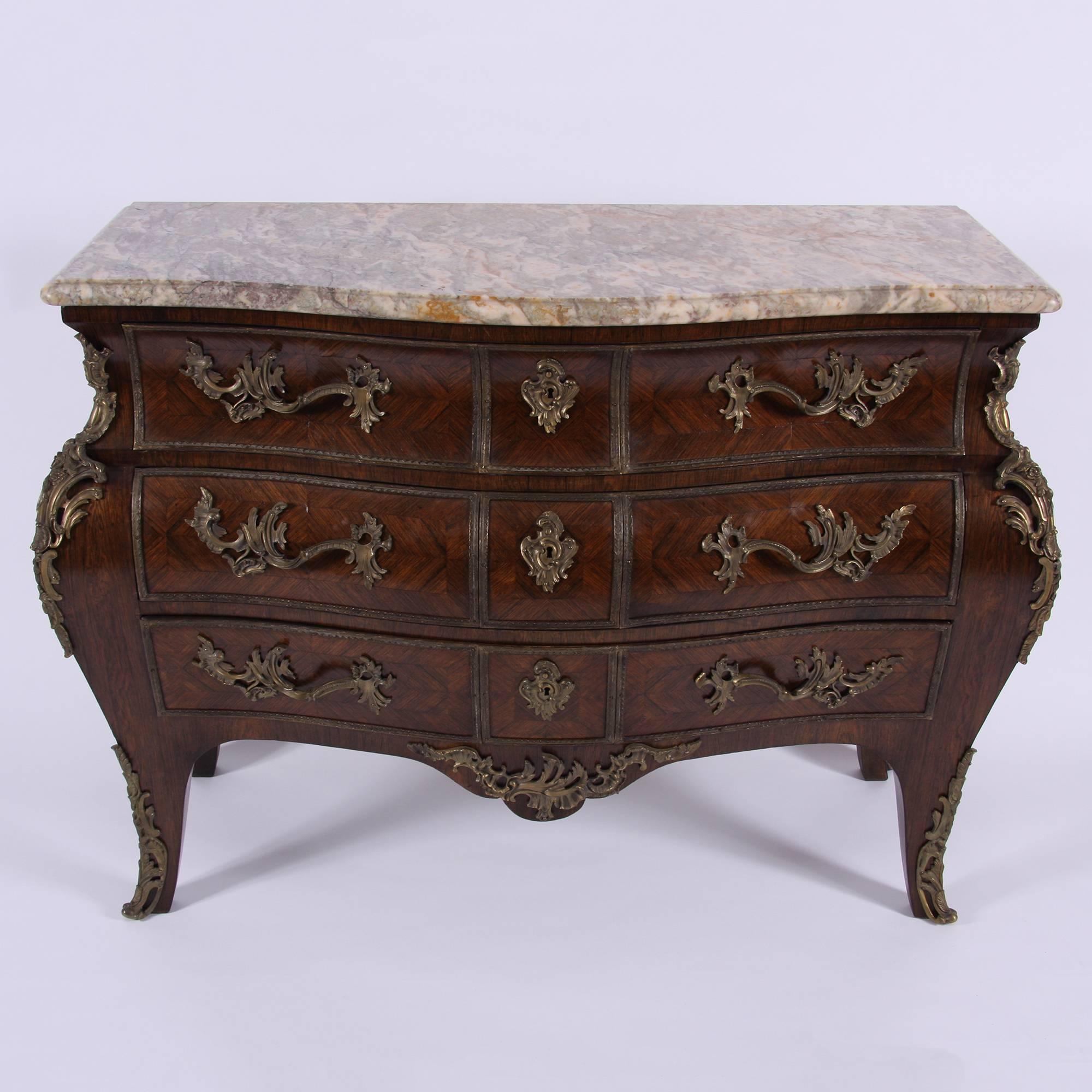 A stunning French hardwood veneer and gilt metal mounted chest of drawers in a Louis XVI style, in bombe shape. With a variegated grey marvel top above three long drawers.