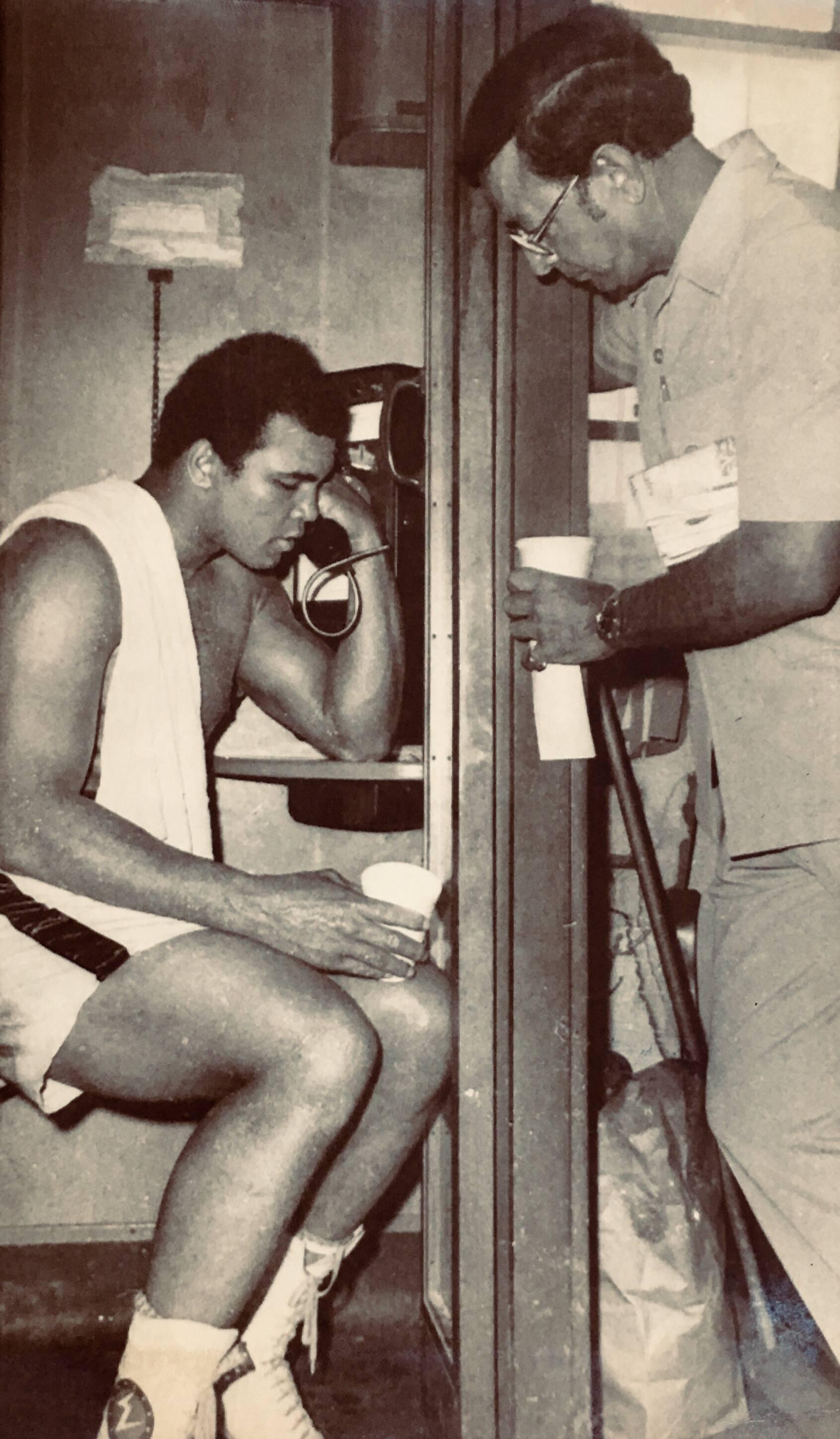 Muhammad Ali, vintage original press photo circa late 1960s-early 1970s. Photographed in Miami alongside noted Ali trainer Angelo Dundee and used as a press piece to announce Ali's forthcoming fight with Joe Frazier.

Measures approximately 6.5 x
