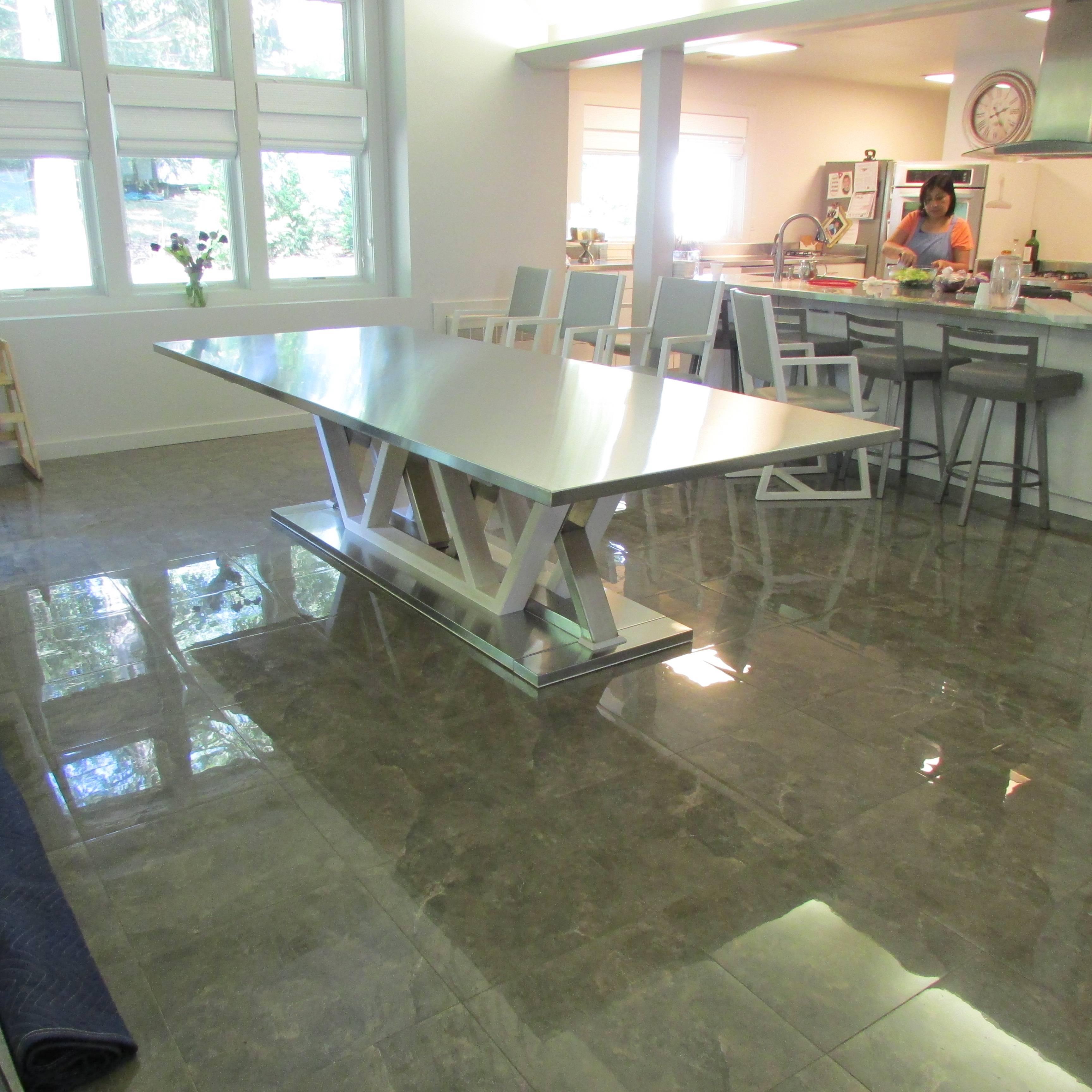 A sleek, original design dining room table. The base is made of stainless steel sheet and tubing with a brushed finish, and wood. The top is stainless steel.

Table can be ordered with custom size tops, and any wood with any finish desired. Price