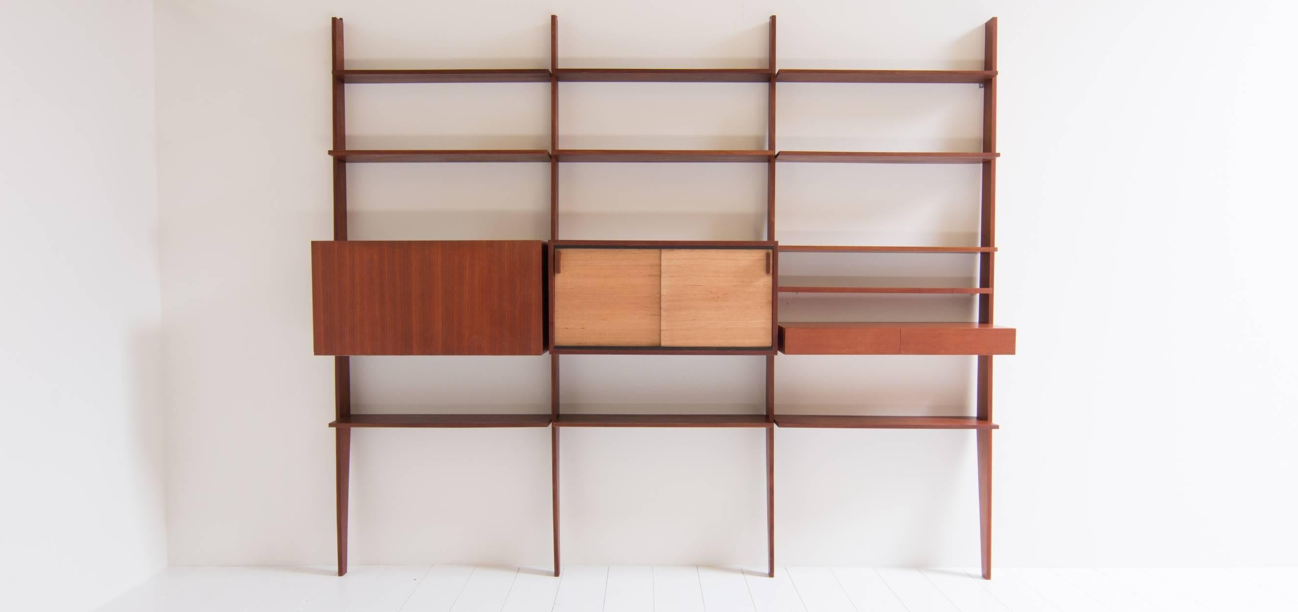 This Dieter Waeckerlin wall system was designed in the 1960s. The wall system was designed by Dieter Waeckerlin for the German manufacturer Behr Møbel. The complete system is made of teak wood. The shelves are all made of massive teak except for