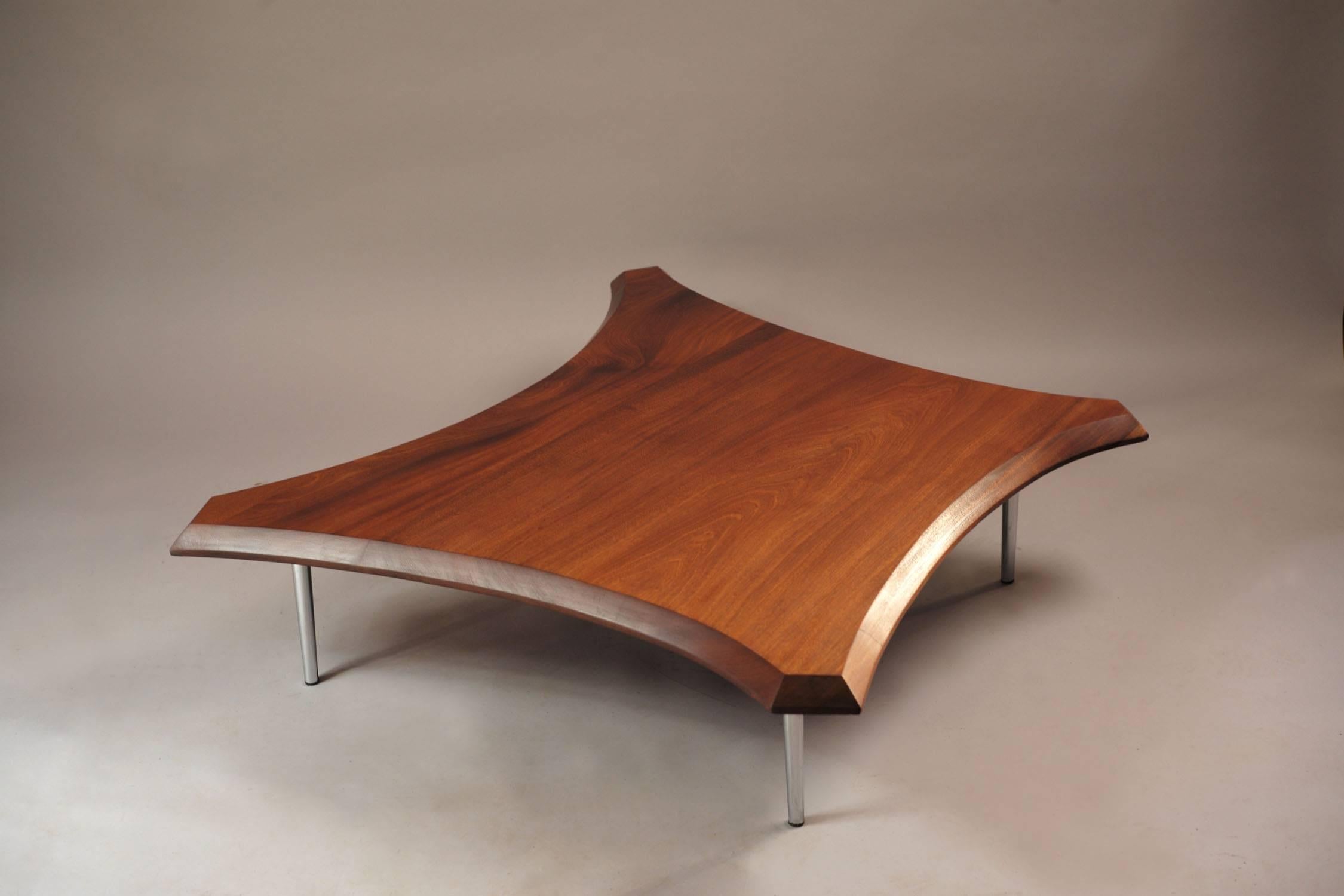 This large coffee table originates in the 1960s and is made from solid mahogany in a free-form shape. It sits on chromed metal legs with beveled and curved table edges. Very nice condition.