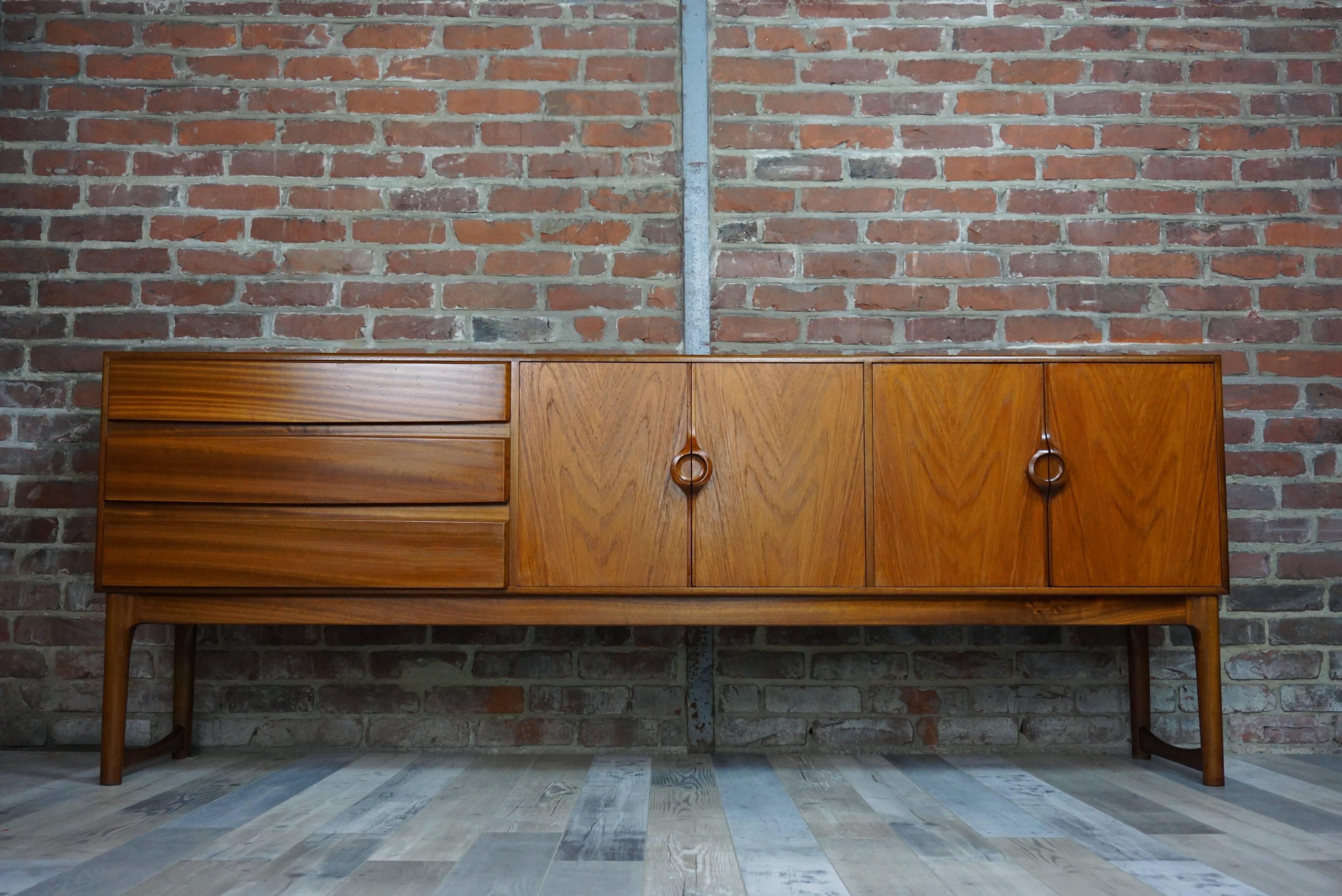 Scandinavian look indisputable for this sideboard of the 1960s (1968 exactly) resolutely modern at the same time. This unusual McIntosh (stamped) credenza has a teak structure, a U-shaped base, sculpted button-shaped handles, three profiled drawers