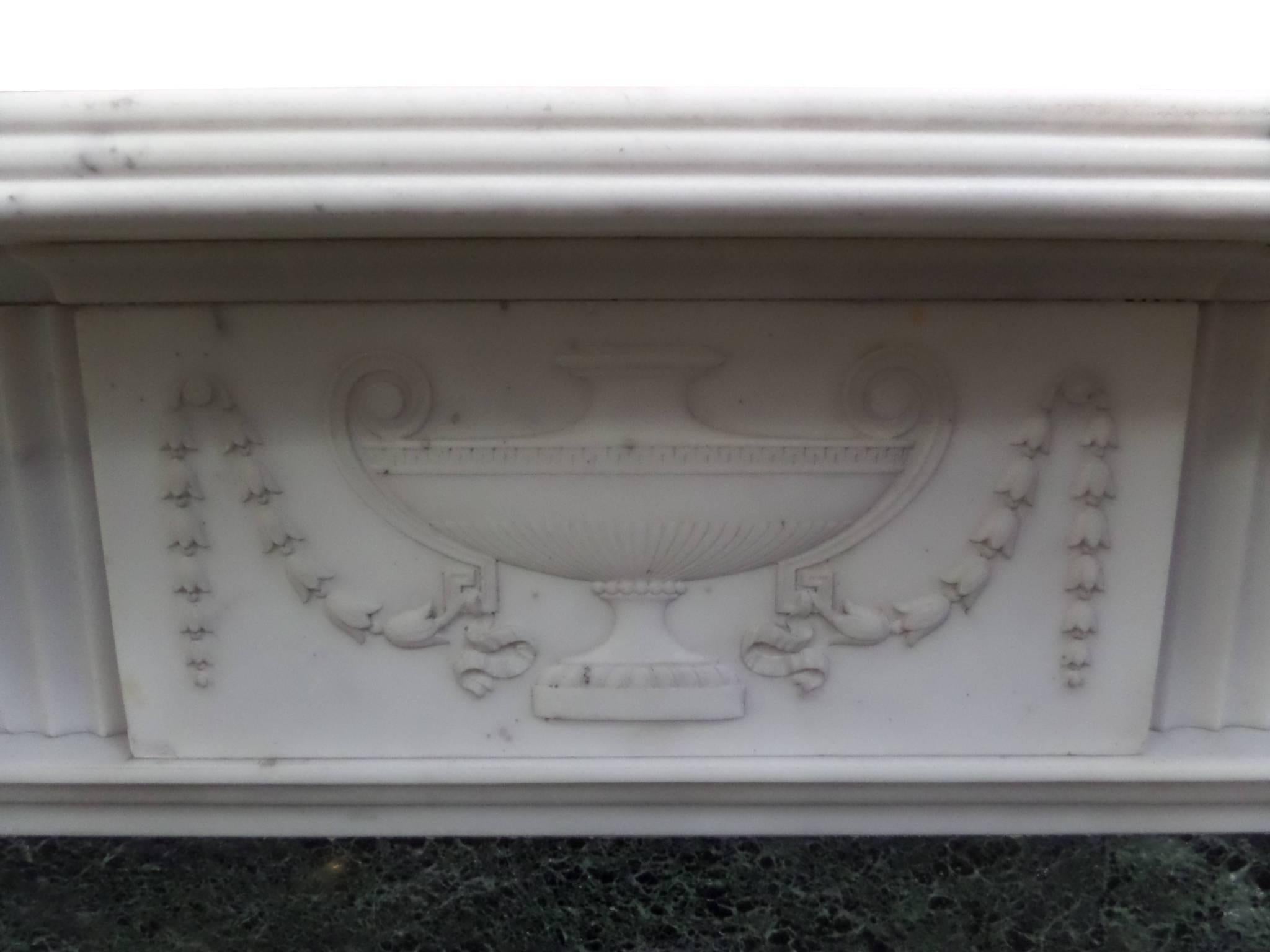 Antique restored Georgian marble surround, a fine antique Georgian statuary marble surround with green Connemara slips, the capitals and the frieze are decorated with carved urns leading up to a traditional bird beak shelf, circa 1890. This