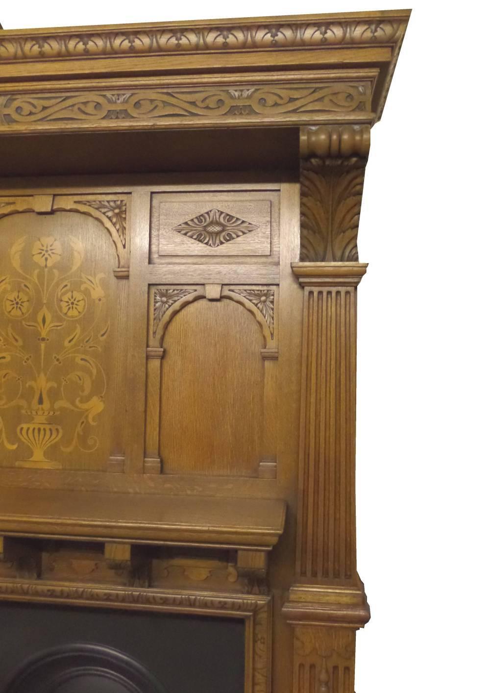 Antique restored late Victorian large oak surround. A large oak surround from a Victorian property in London England. Beautiful inlay panel work and wood carving. Fluted grand pillars with leafed carving under the shelf and around opening, circa