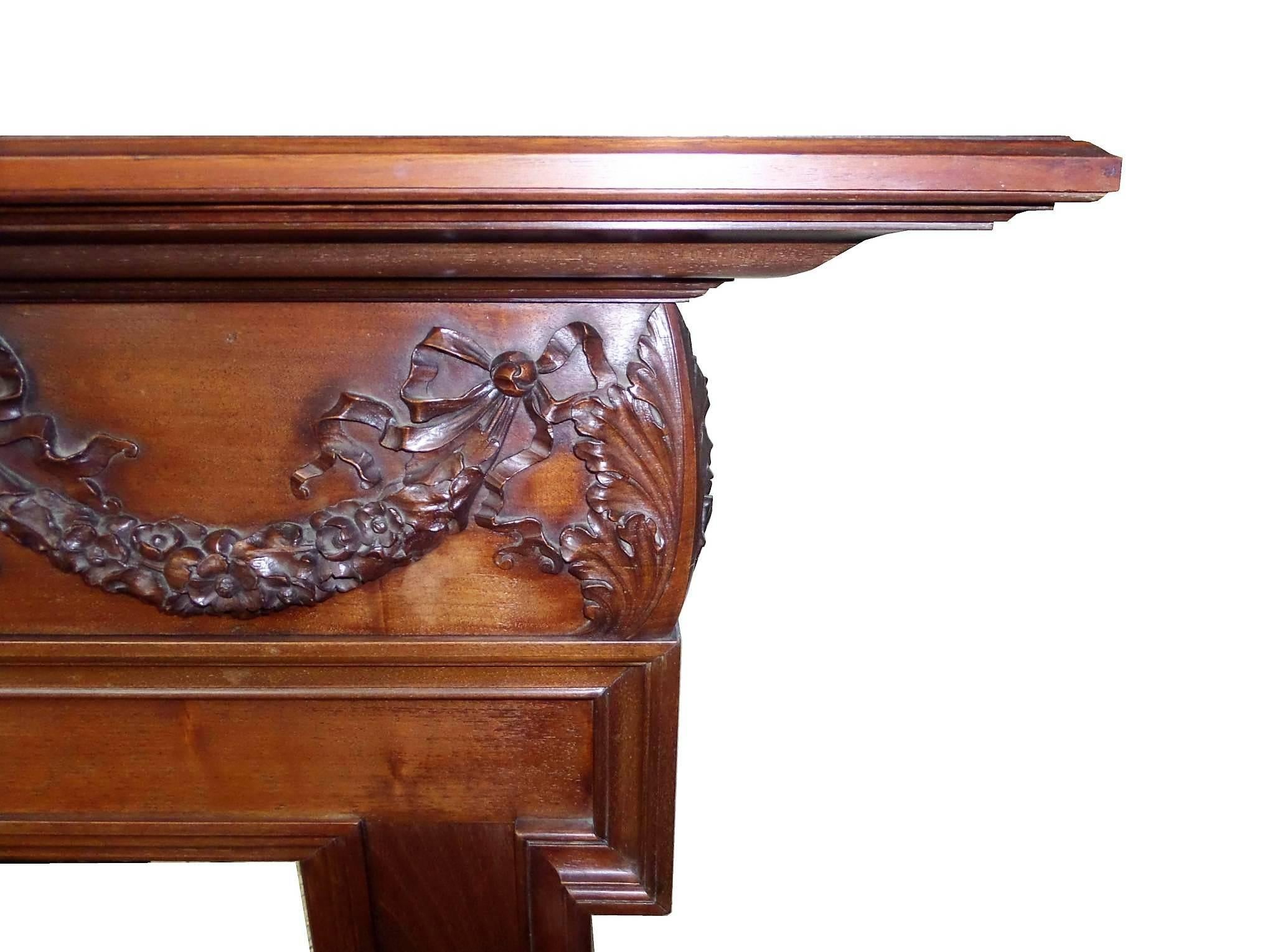 Antique restored Georgian walnut wood mantel / surround. The surround across the freize features a hand carved Robert Adam style Georgian swag on walnut wood, circa 1800.