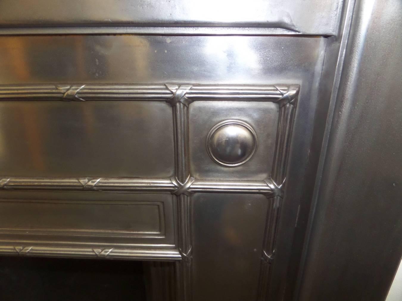 Antique restored 1920-1930 cast Iron burnished Interior with cast roundals and cross band moulding. A fine example. Complete with a new fabricated metal fire back, front bars, ash cover and grate.