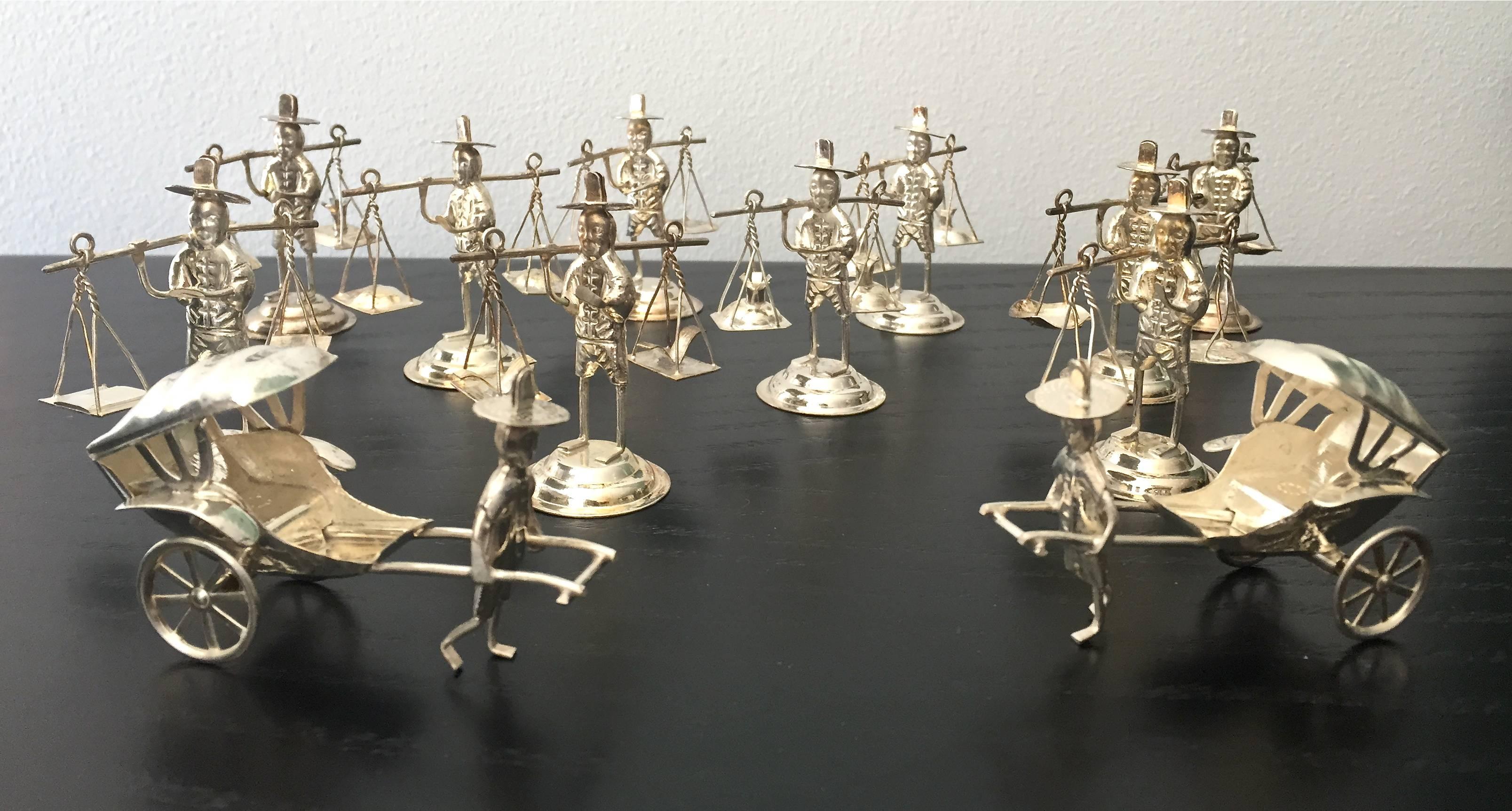 Set of 12 silver plate place card holders in the form of orientalist Chinese figures.

Size indicated in the measurement description field is the size of the ten standing figures. Measurement of the two rickshaw figures are as follows, depth 3