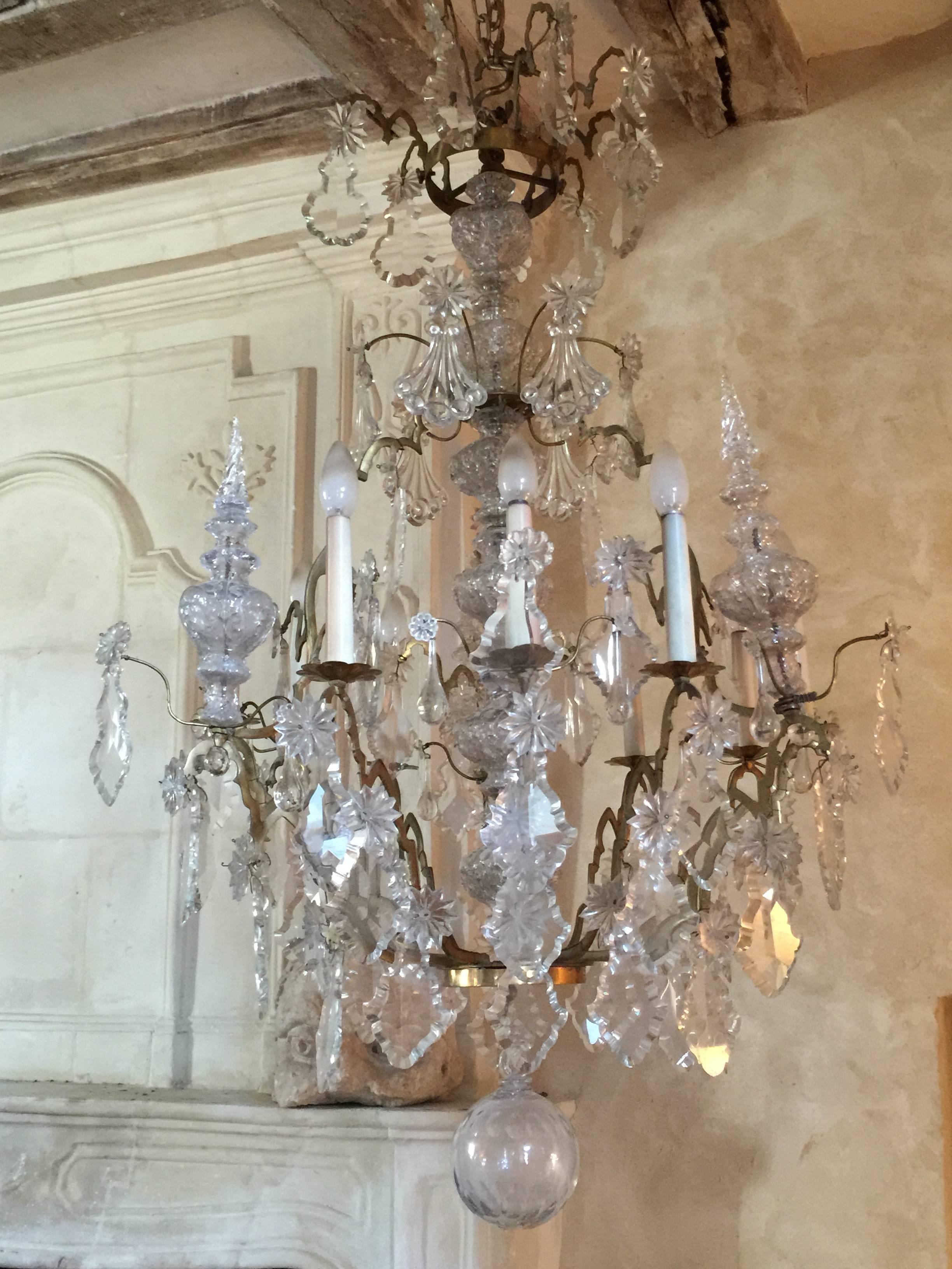 Baccarat crystal and bronze chandelier with nine curved arms of light decorated with pendants, tassels, rosettes and an alternation of transparent crystal flowers. Three other arms surmounted by pots complete this remarkable ensemble by the fineness