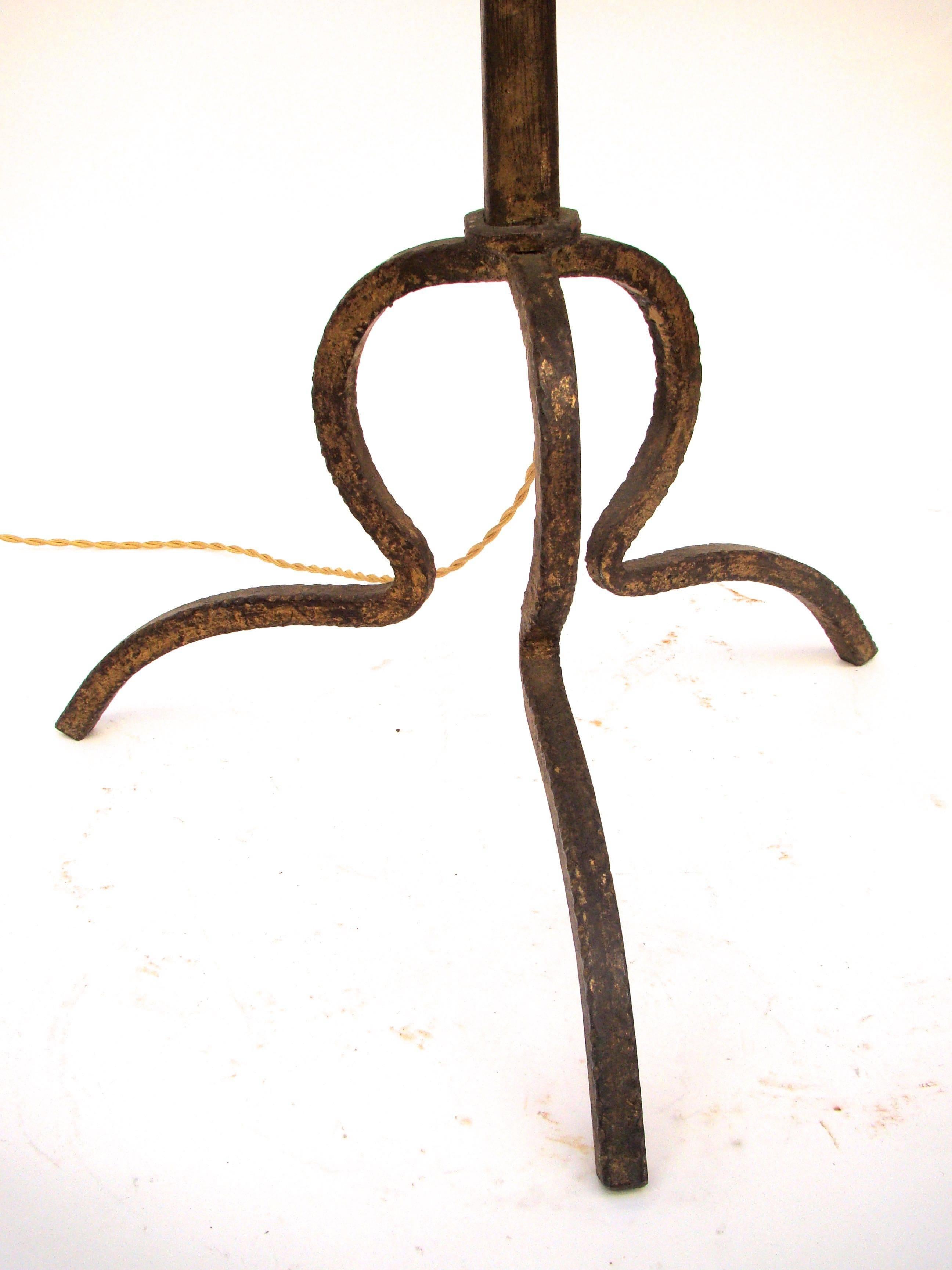 French handsome floor lamp in golden wrought iron decorated with a three legs base, circa 1960.