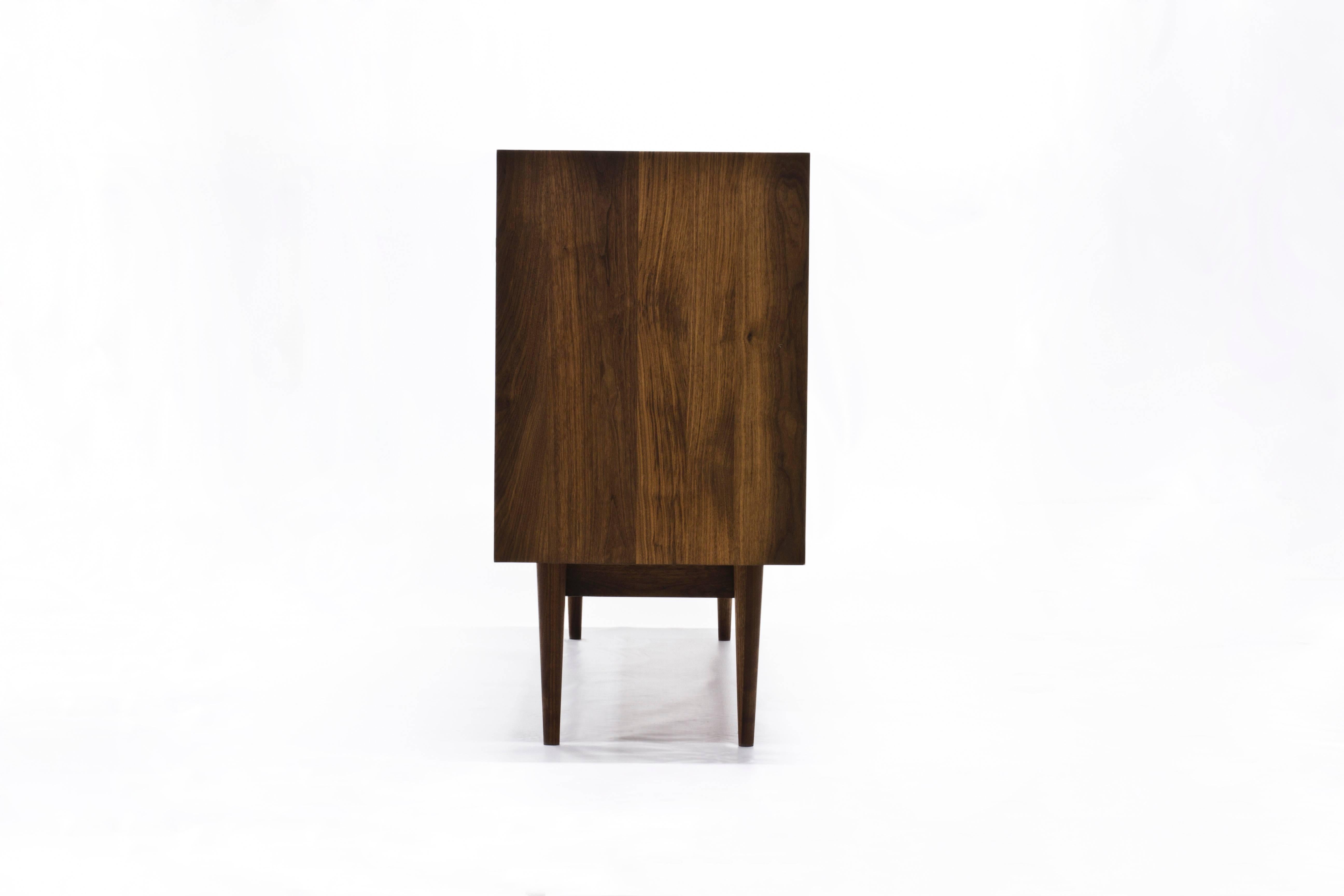 The Sine Wave console by Michael Dreeben for Wooda is a bespoke-quality solid walnut cabinet. The sine waves that ornament the door panels function most immediately as a decorative element. But they also emit the LED light from within the cabinet