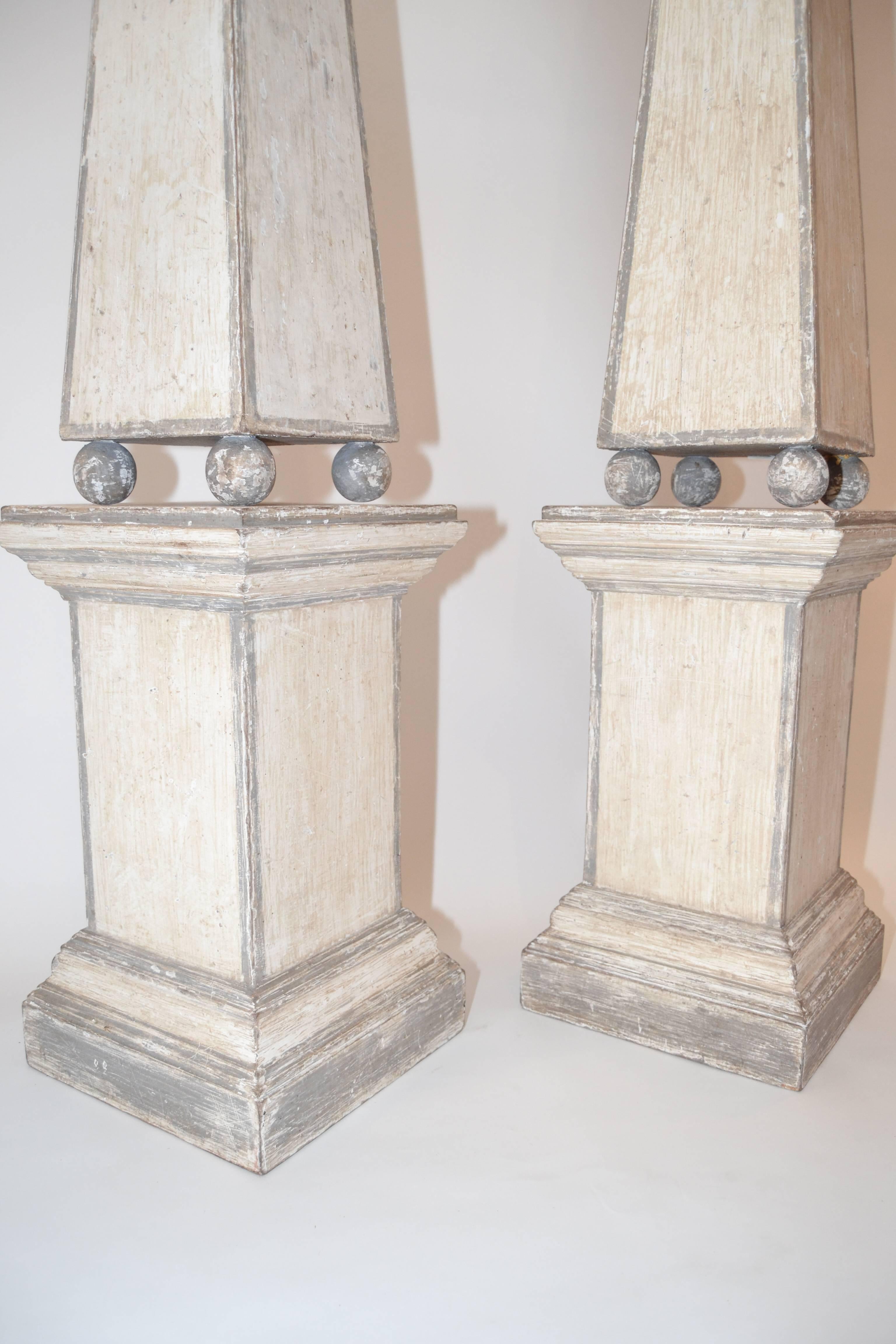 Pair of tall painted indoor pine obelisks on matching bases from Florence, Italy.
Handsome antique white finish banded in gray; these are great for an entrance or conservatory.  