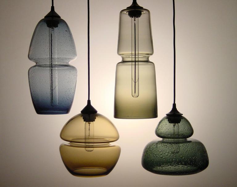 These hanging lights feature an embedded groove that offers a precise, machine-made quality to offset these otherwise wholly handmade creations. Whether showcased individually, as an aligned set or an organic cluster, these designs create a lustrous