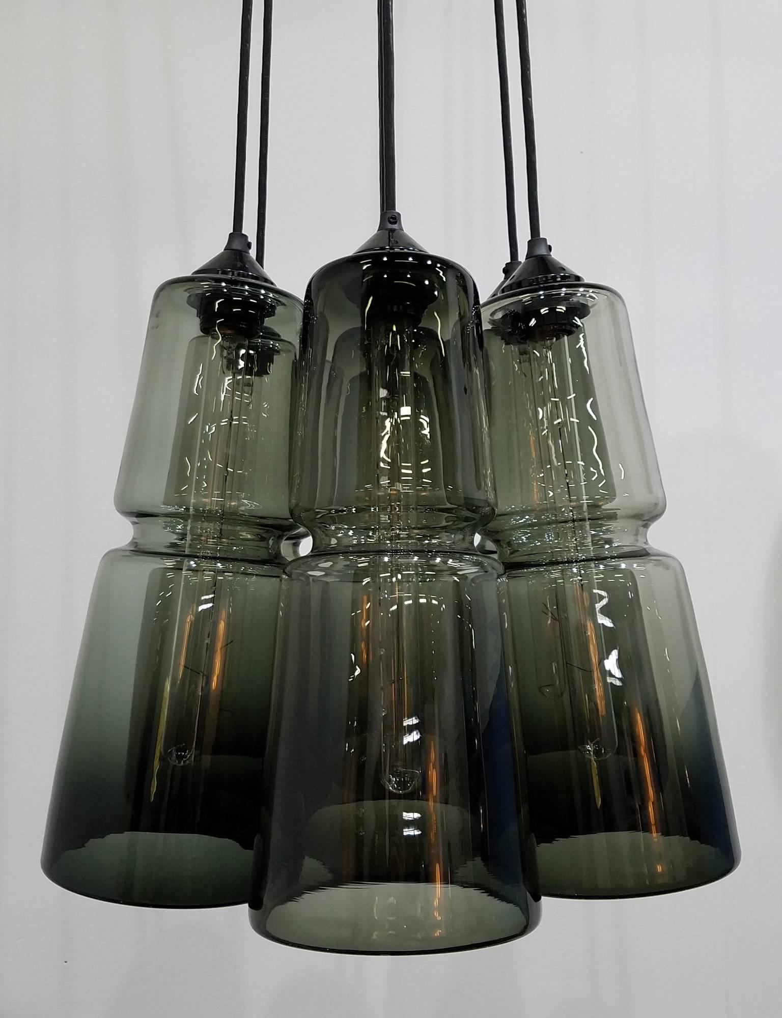 Multiple component chandelier, the arrangement as shown is comprised of seven (7) Groove Series Cylinder pendants which each have an embedded horizontal groove that provides a precise machine-made quality to these wholly handmade designs. Available