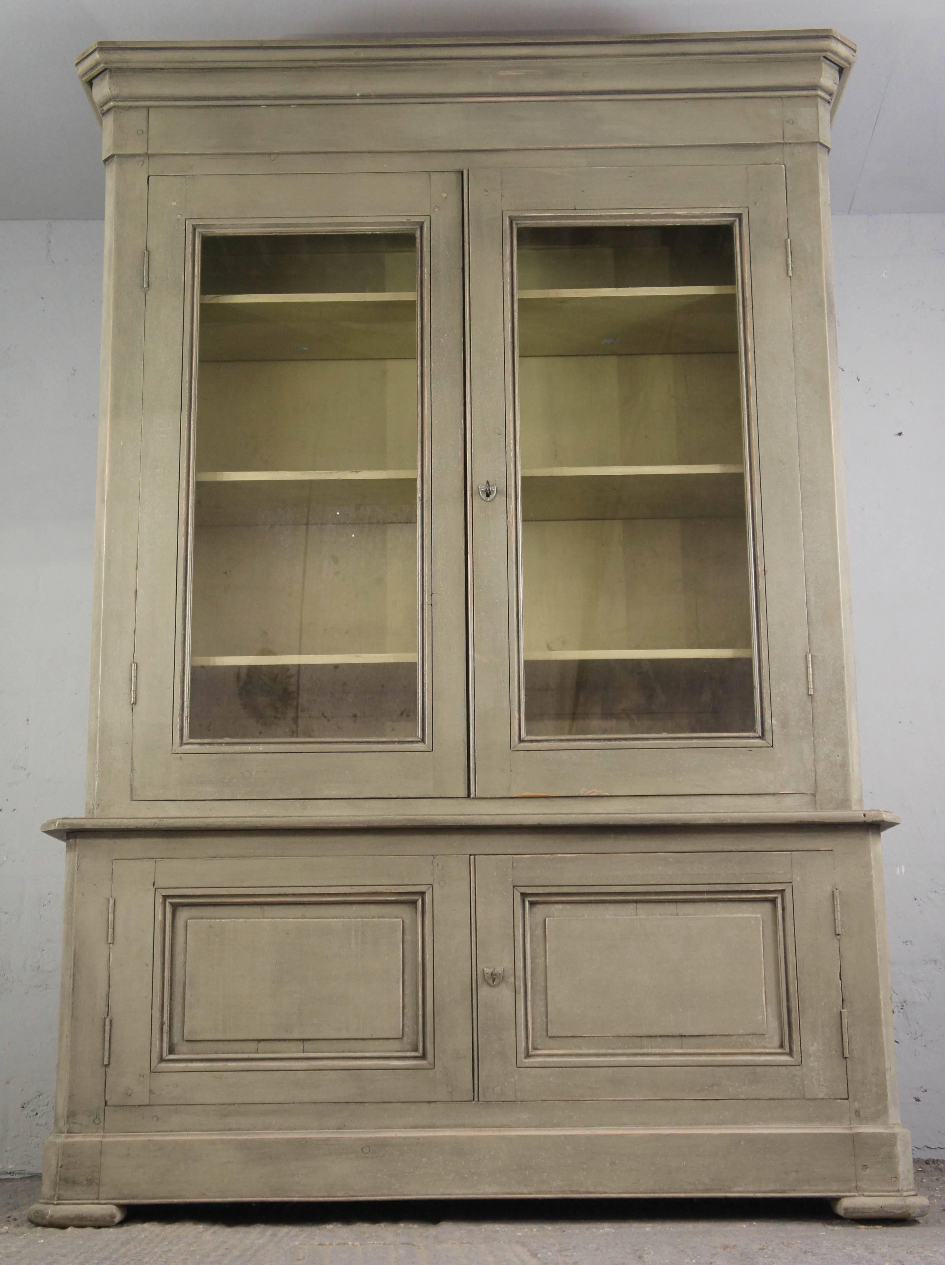 Fabulous 19th century bookcase sourced in the southern region of France. It has been later painted in a sage green paint and a contrasting cream colour inside. The cupboard below features double doors with lock and key and shelf inside. The top