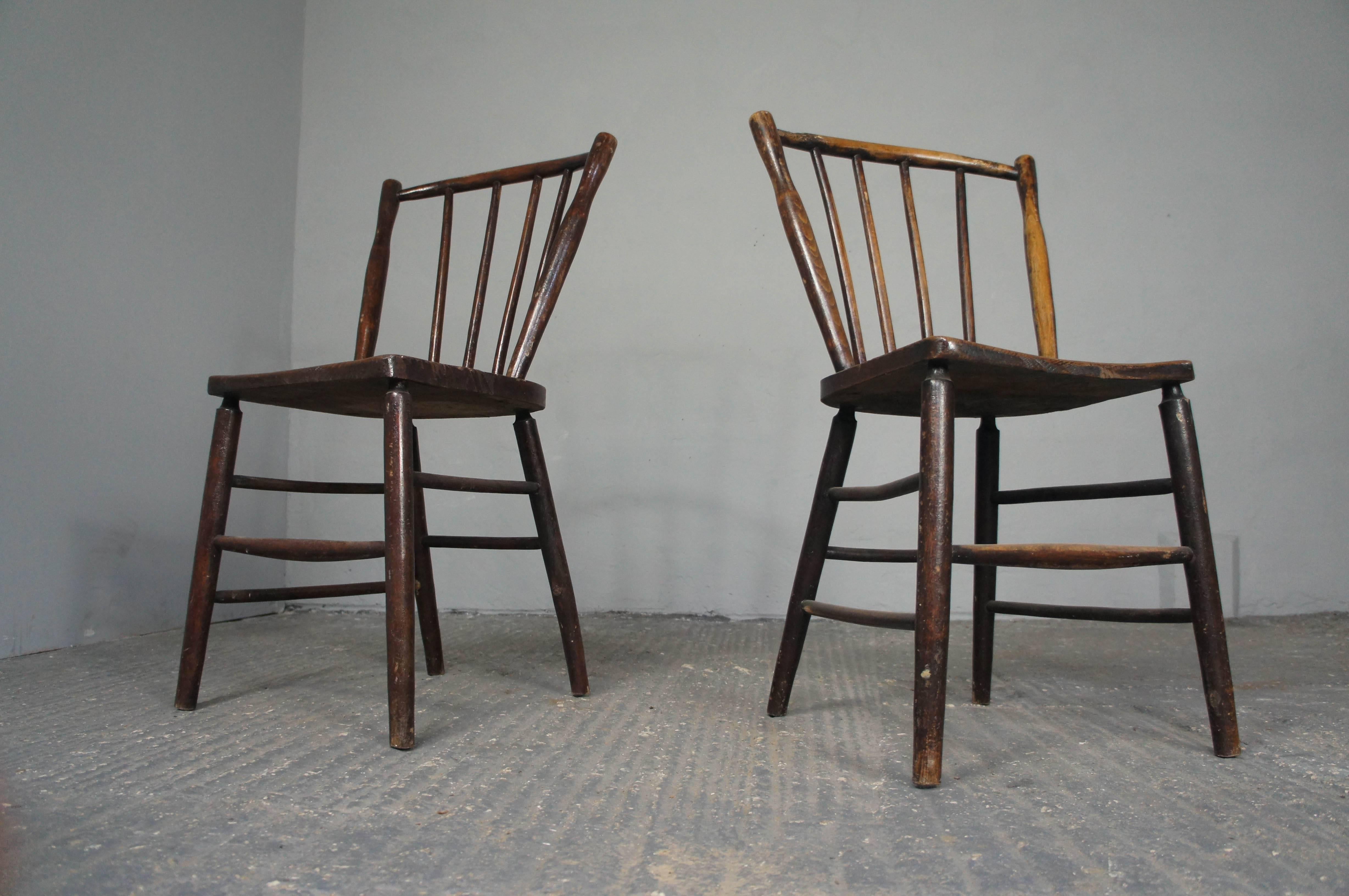 A pair of early Irish spindle back beech kitchen chairs with ash seat. Both chairs are stamped on the back of the seat. Simple, rustic design.