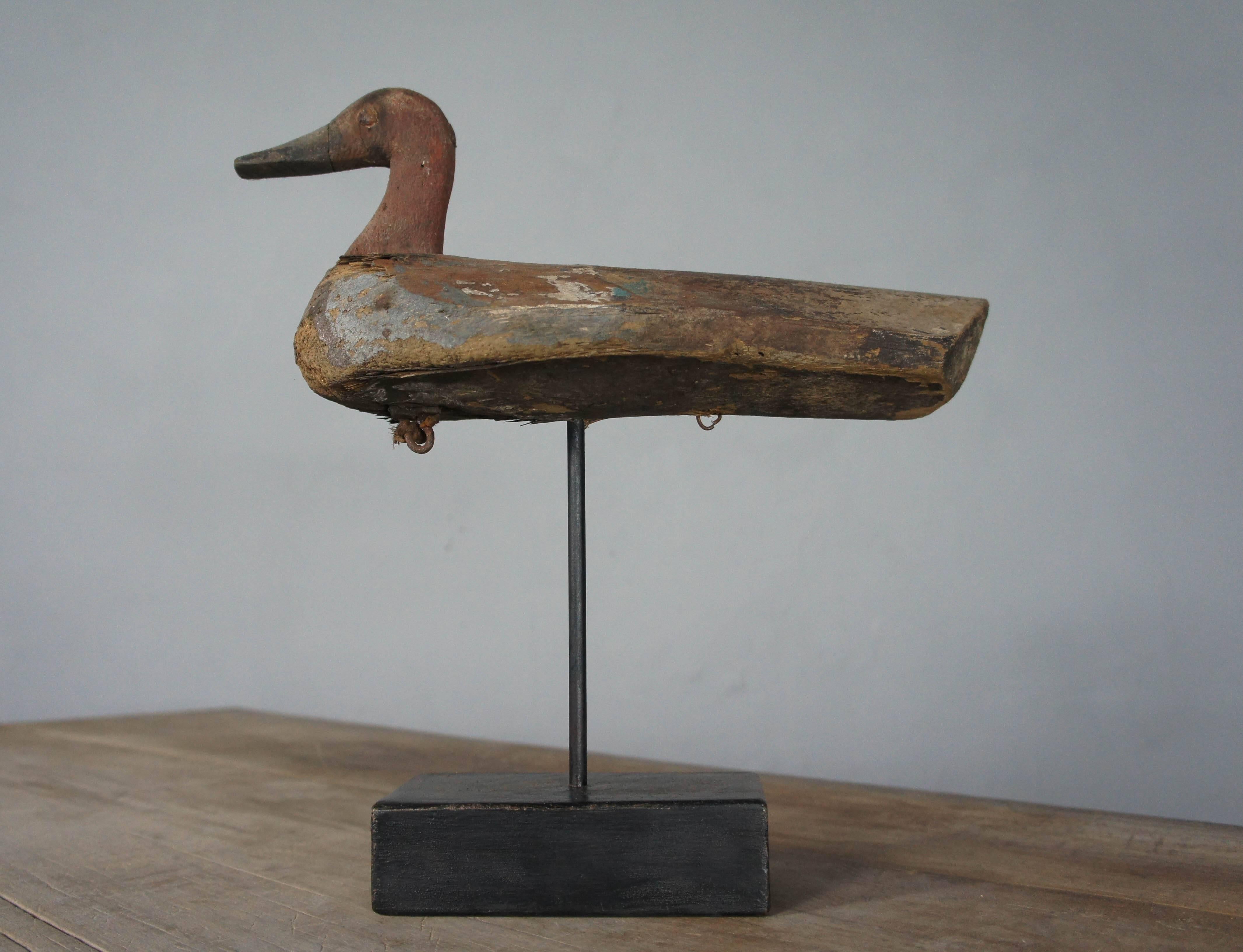 Pretty decoy duck in original paint, which has been mounted on a stand for decorative purposes. It is made from balsa wood which was the perfect material for floating decoys. A few losses consistent with age and use, great chippy paint.