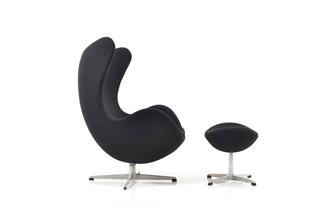 'The Egg', model 3316 and footstool model 3127. Design by Arne Jacobsen. Manufactured by Fritz Hansen in 1963. 2010 new upholstered in black Kvadrat Hallingdal fabric.

Size: 79.0 x 86.0 x 107.0 CM (D x W x H), seat height: 37.0 CM, footstool: