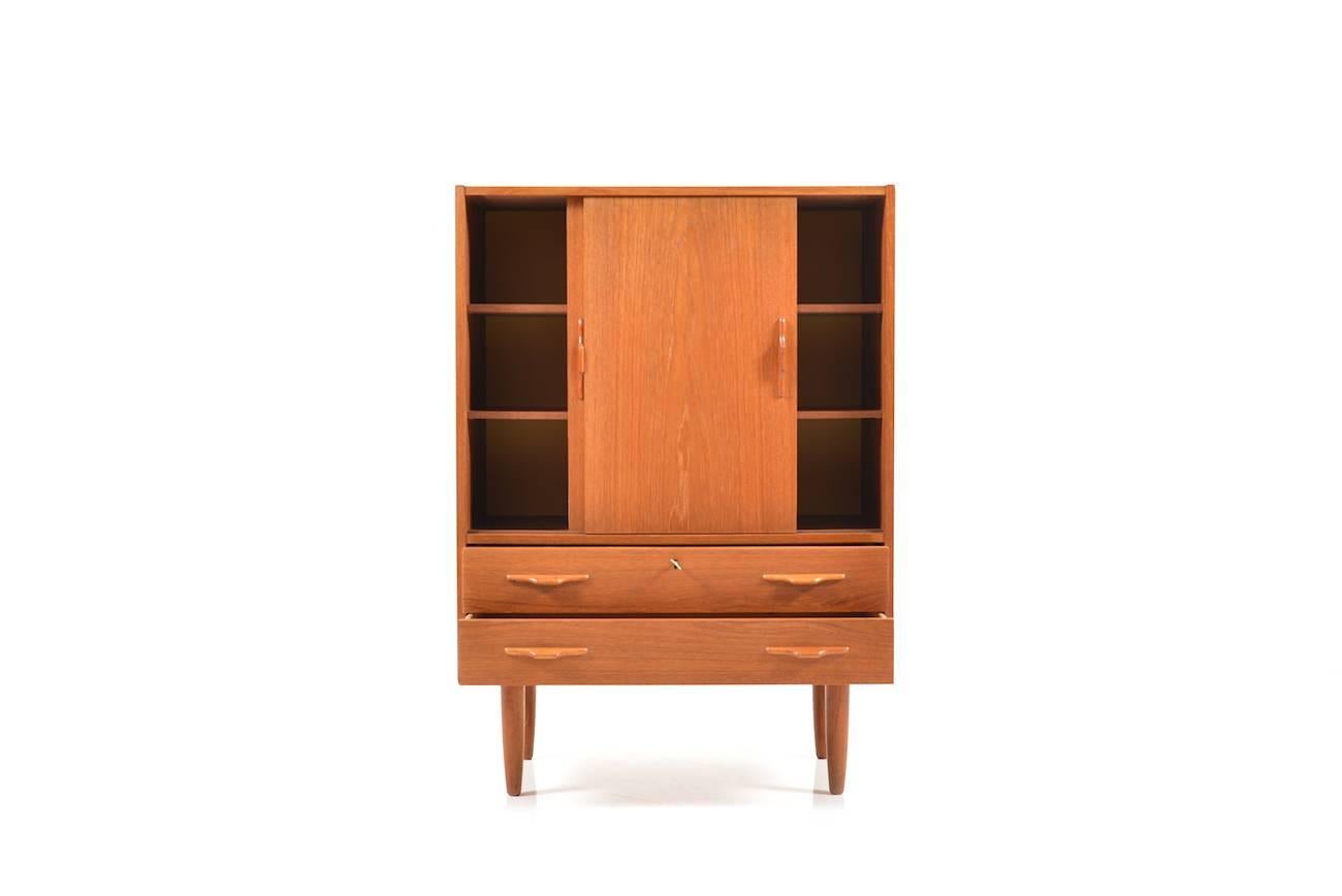 Fine Danish teak cabinet from the 1950s. Front with two drawers and two sliding doors. behind the doors with shelves. Incl. 1 key. Very good vinatge condition.
