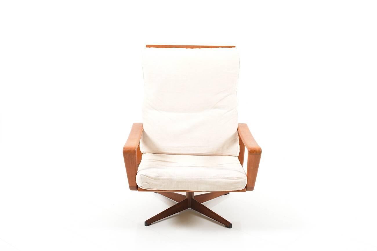 Swivel lounge chair by Arne Wahl Iversen for Komfort, Denmark, 1960s. Teak wooden frame with metal cross feet in teak veneer. Original stand from the 1960s. Original cushion in light fabrig with use of trace. Woo in very good condition.

Note: see