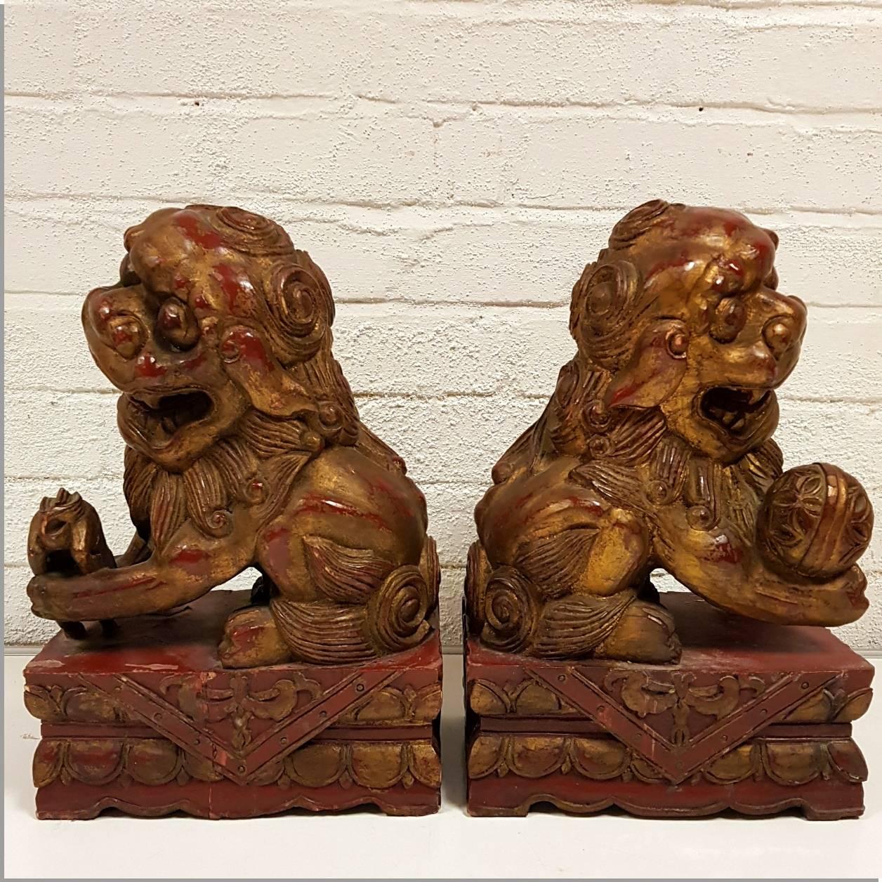 Pair of large late 19th century hand-carved wooden Chinese foo dog figures. Remnants of red lacquer and gilt decoration still visible. Matching pair with the female (with cub) and male (with ball). According to the teachings of Feng Shui, there is a